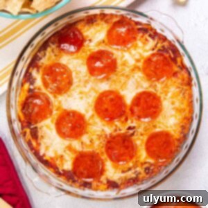 Top down view of pizza dip baked in a pie plate. The dip is topped with pepperoni and the cheese is bubbly and golden.
