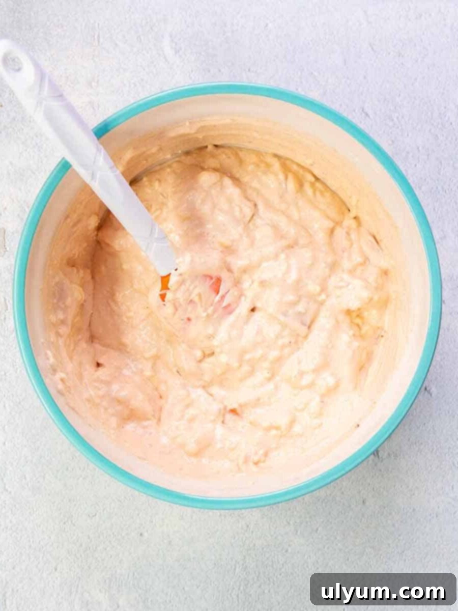 Pizza dip cream cheese mixture combined in a bowl with a spatula.