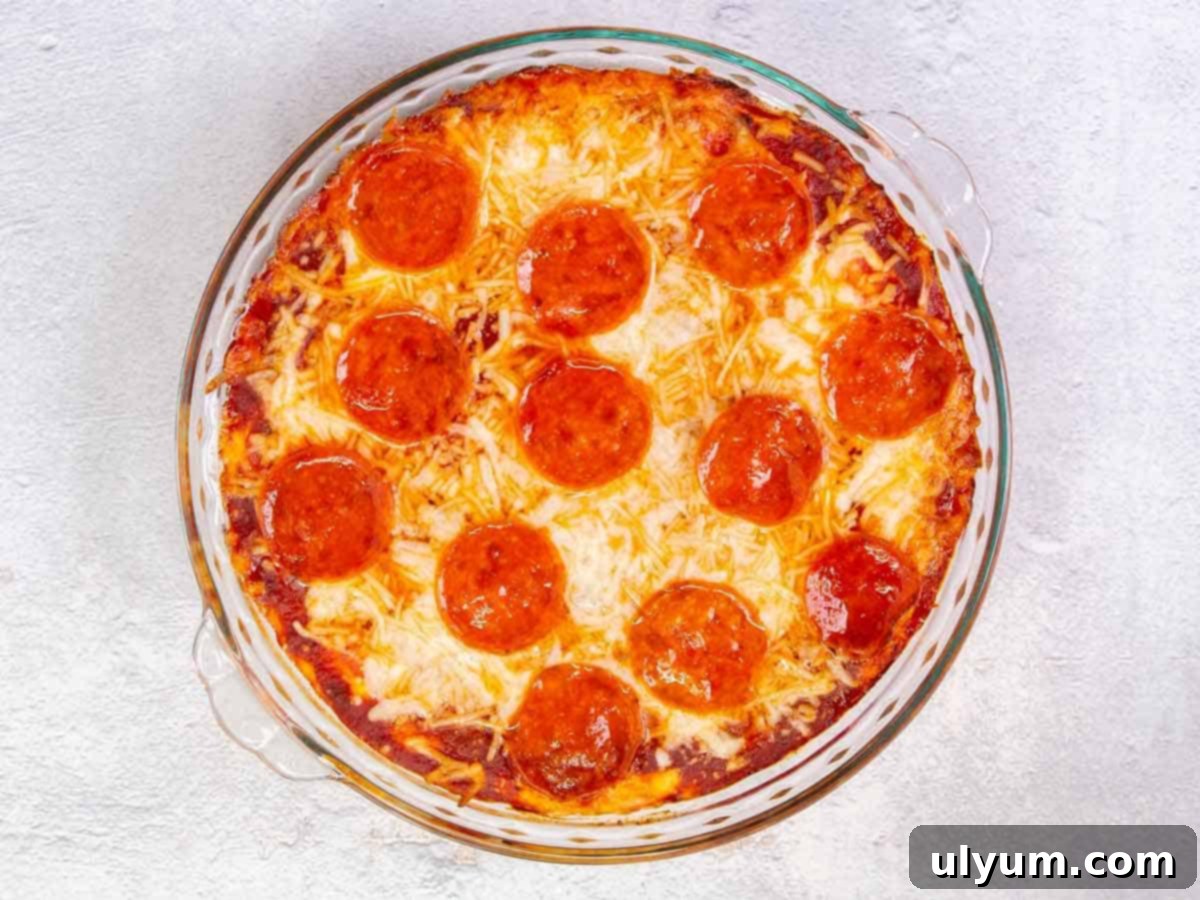 Top down view of pizza dip baked in a pie plate. The dip is topped with pepperoni and the cheese is bubbly and golden.