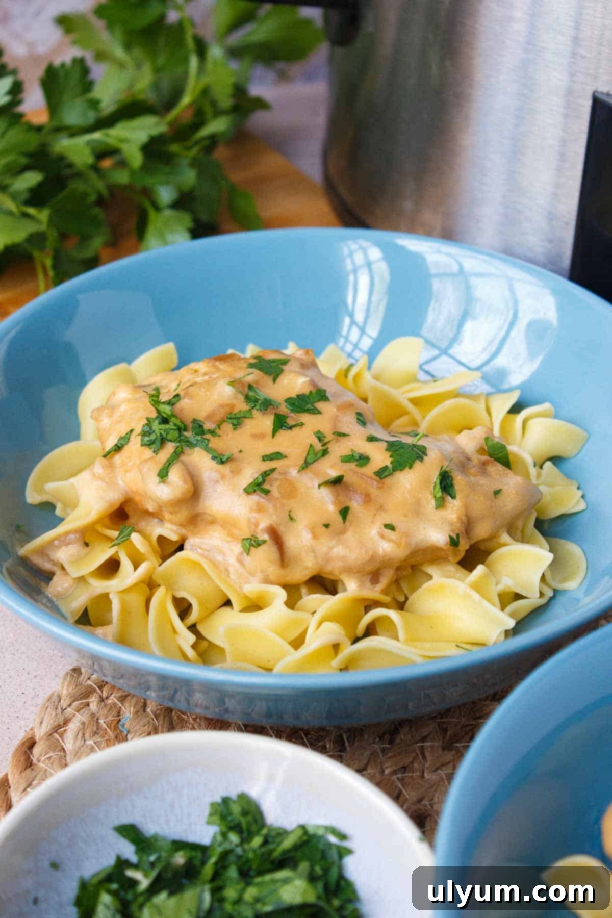4-Ingredient Crockpot Chicken served on egg noodles with a sprig of fresh parsley