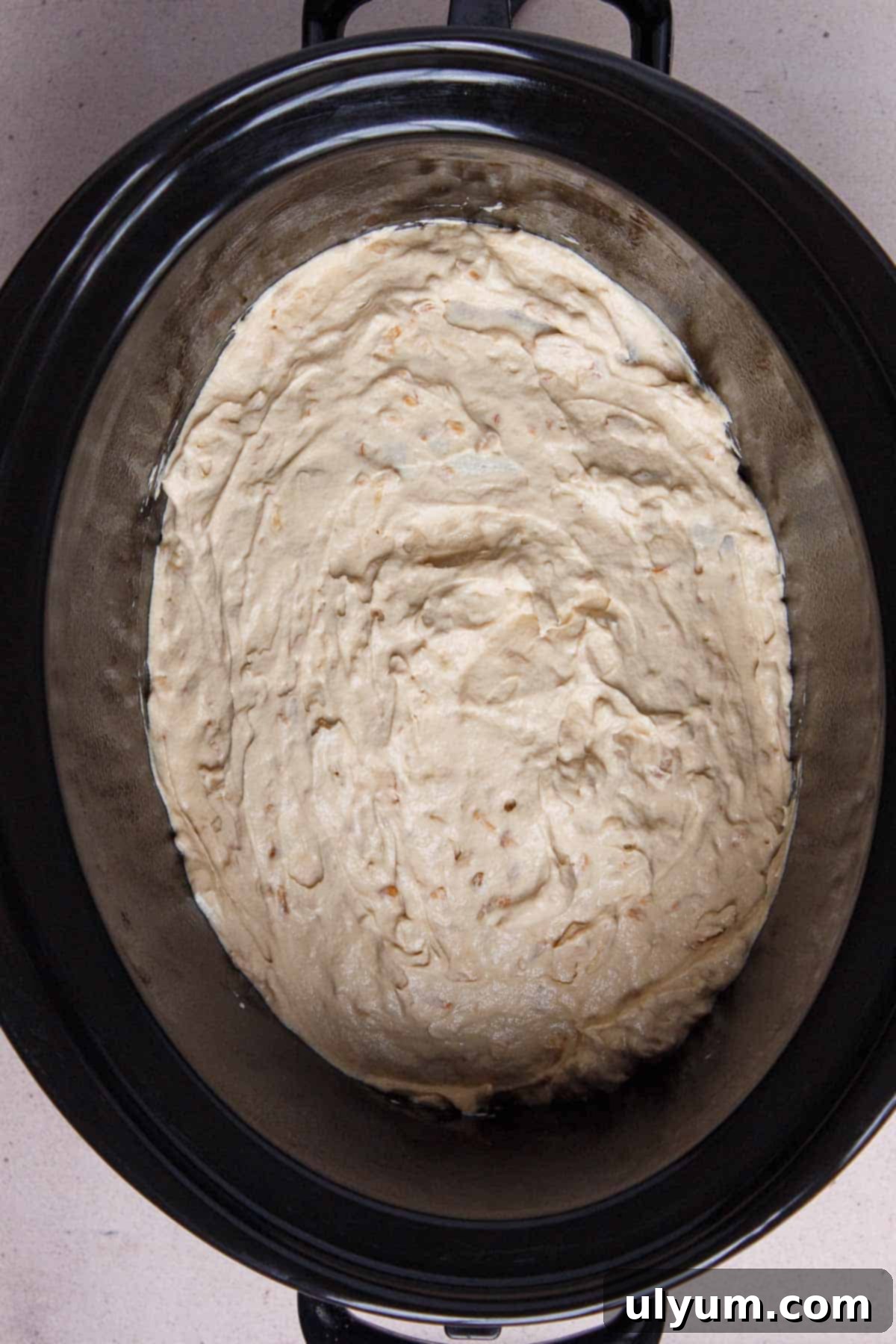 Creamy soup mixture spread evenly over chicken breasts in the slow cooker