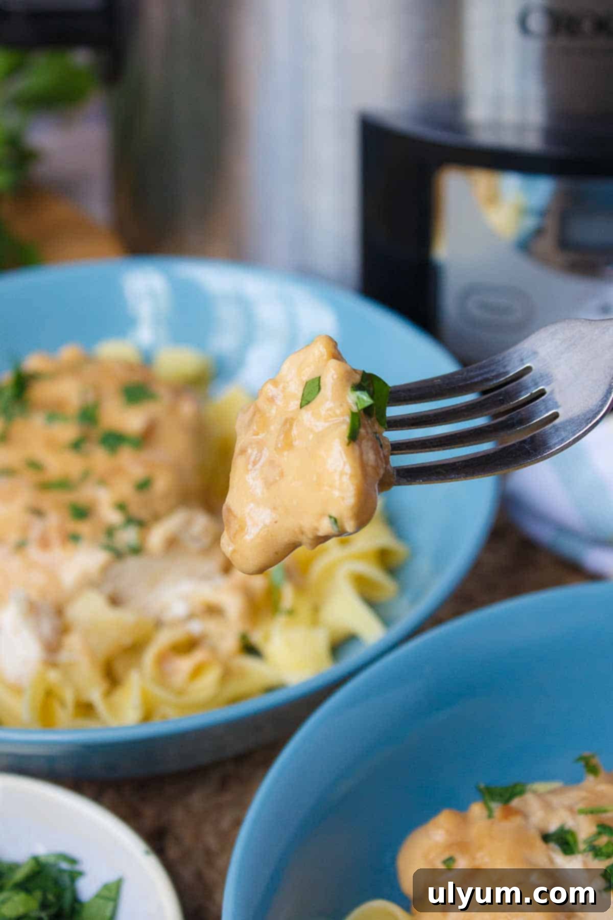 A fork holding a delicious bite of 4-Ingredient Crockpot Chicken, showing its creamy texture