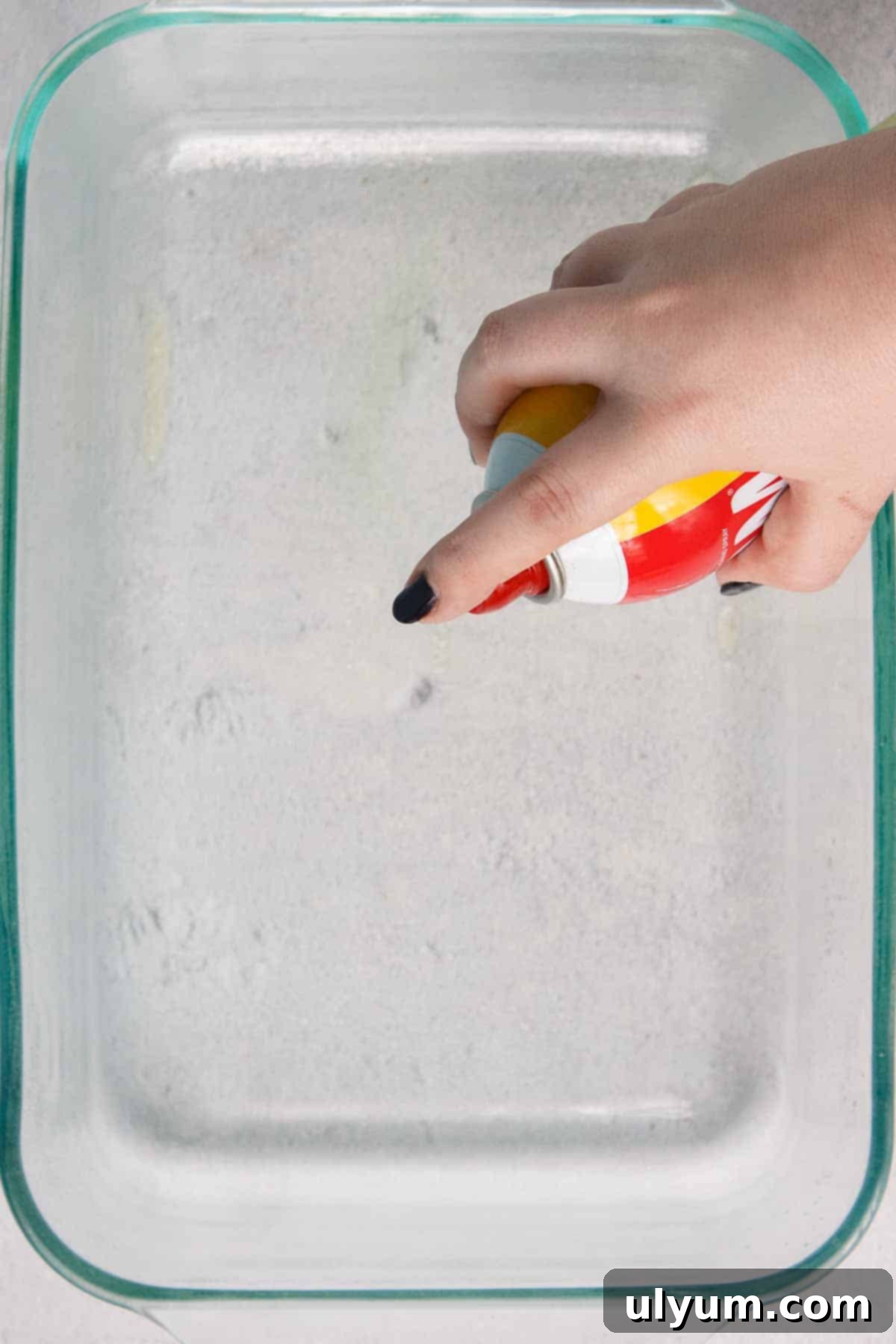 Spraying a 9 by 13 baking dish with cooking spray