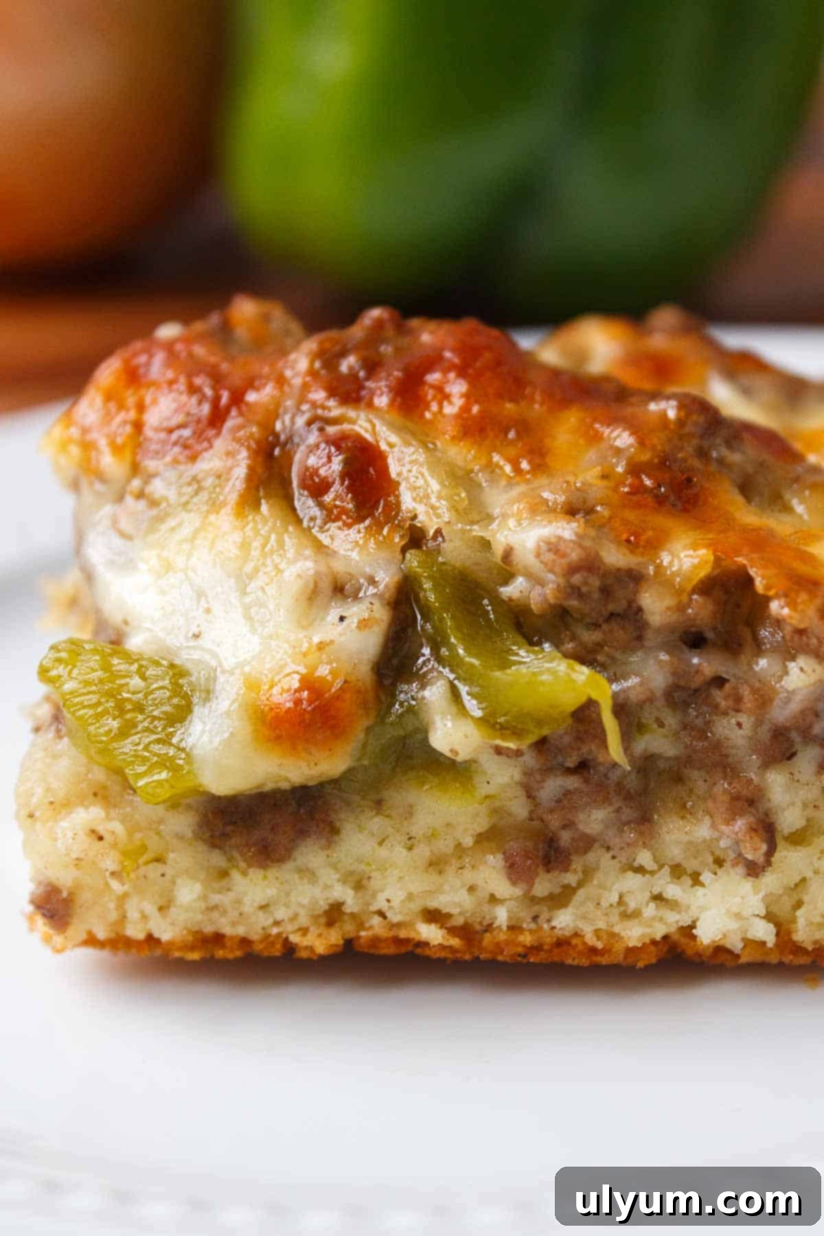 A large serving of Philly cheesesteak casserole with a golden crust and melted cheese, showcasing the rich filling inside.