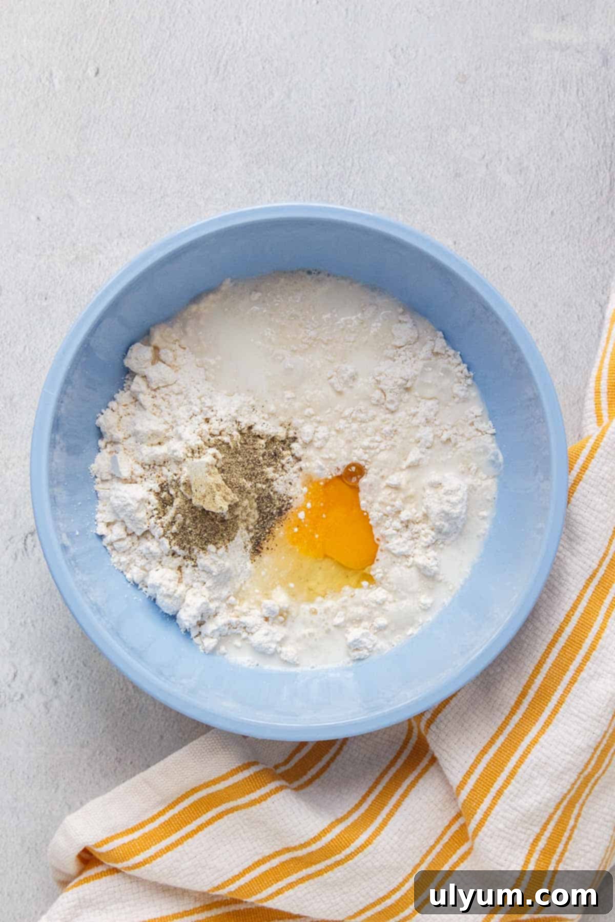 Bisquick mix, milk, egg, and black pepper combined in a mixing bowl for the biscuit batter.