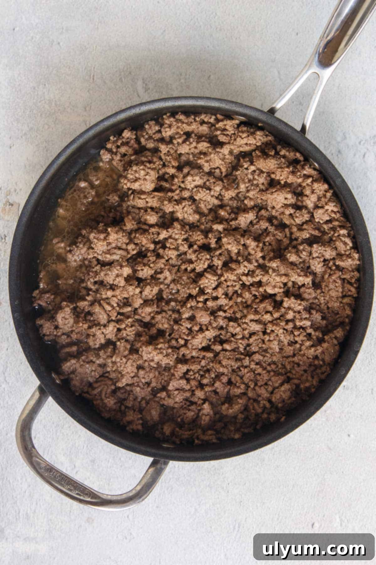 Ground beef cooking in a large skillet, browning evenly to prepare for the casserole filling.