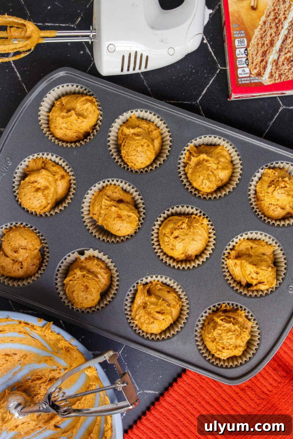 Pumpkin muffin batter distributed evenly in a lined muffin tin