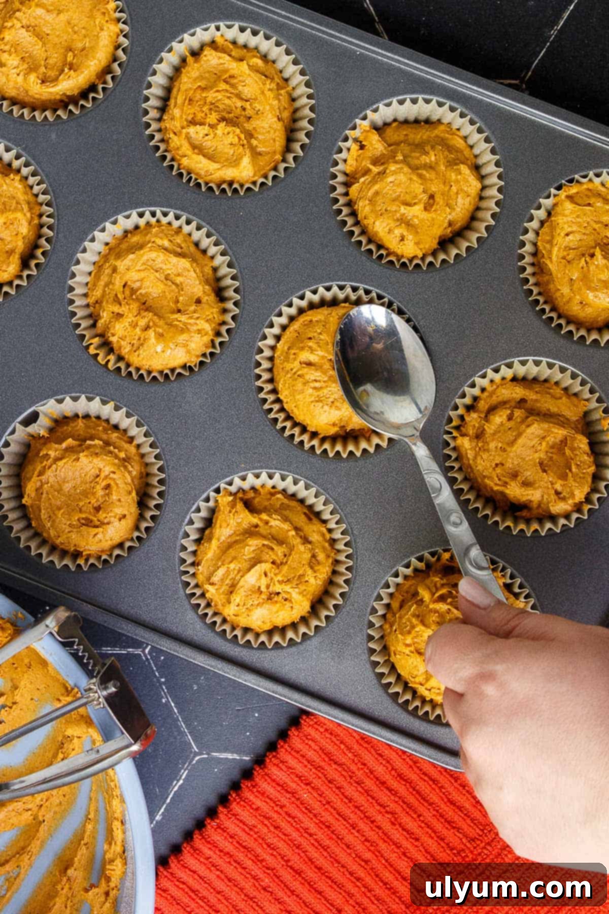 Smoothing the top of the muffin batter with the back of a spoon to make the tops less lumpy