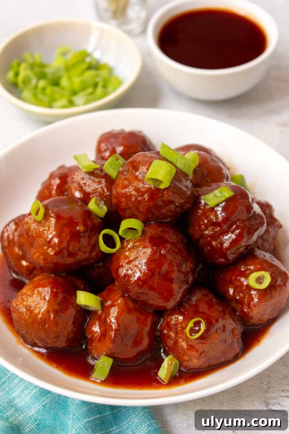 Instant Pot Grape Jelly Meatballs garnished generously with sliced green onions in a large serving bowl.