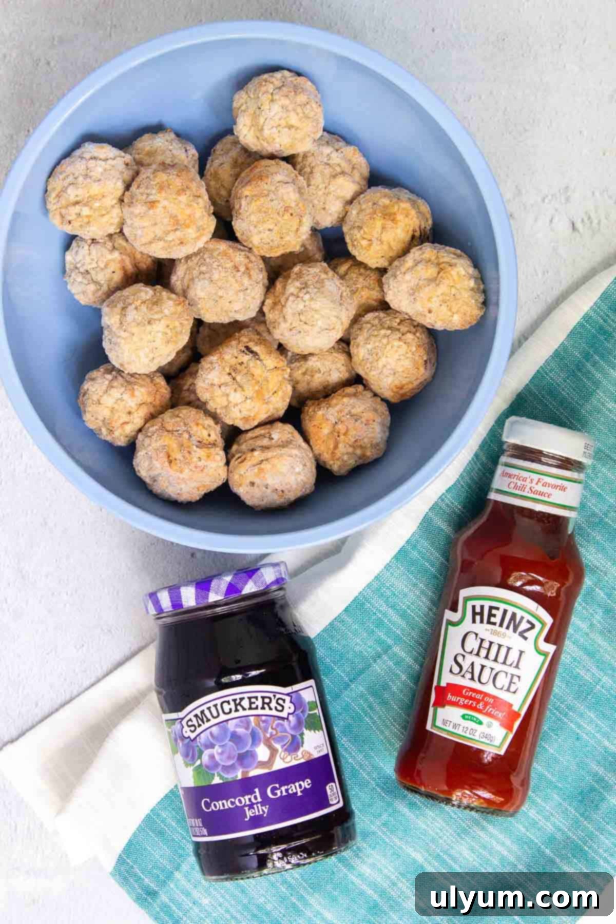 Close-up of the essential ingredients for Instant Pot Grape Jelly Meatballs: Concord grape jelly, Heinz chili sauce, water, and frozen meatballs.