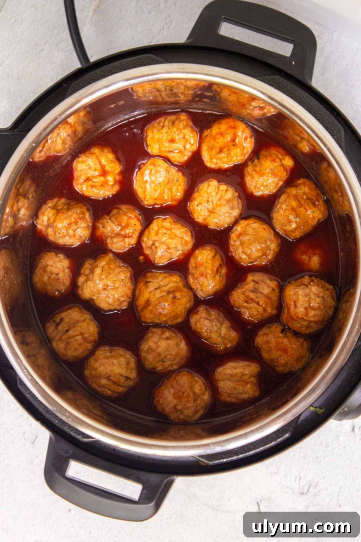 Frozen meatballs added to the Instant Pot and coated in grape jelly sauce.