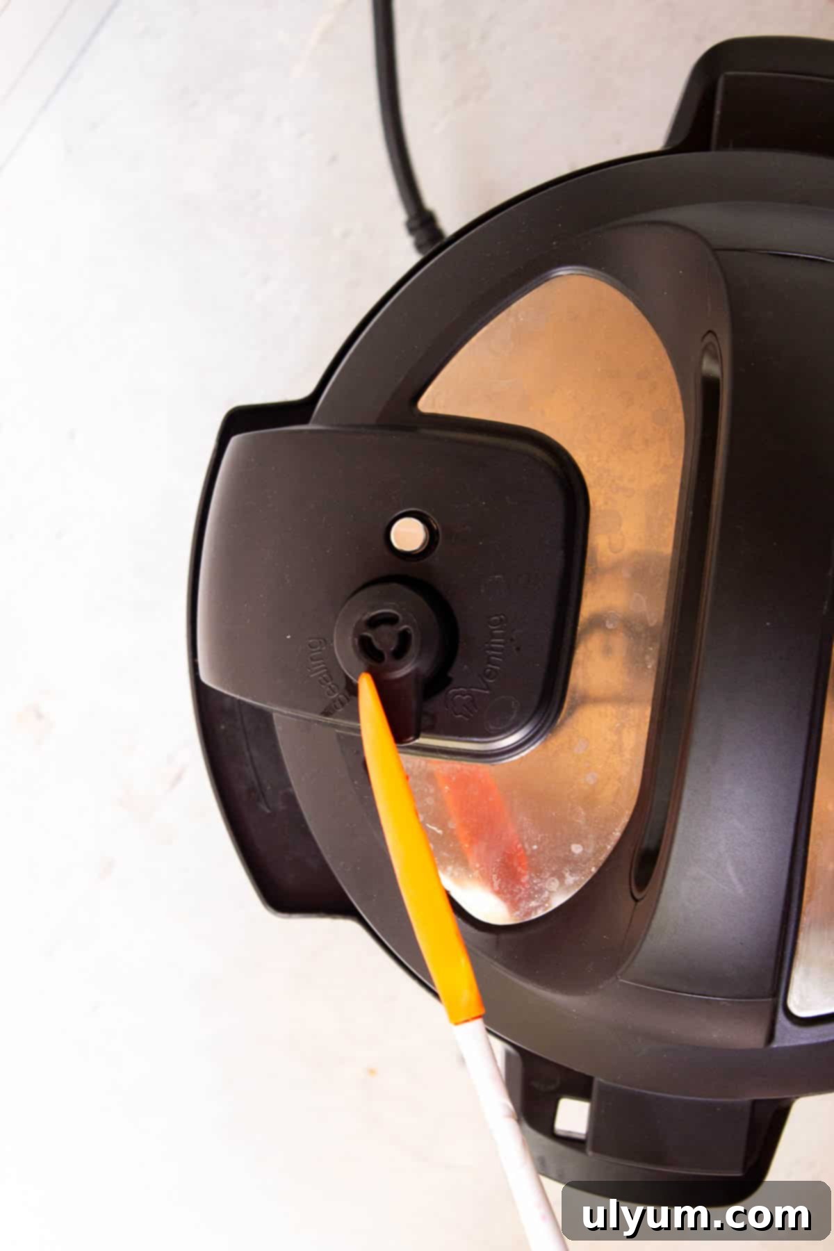 Turning the Instant Pot pressure knob to venting using a silicone spatula to quick release pressure.