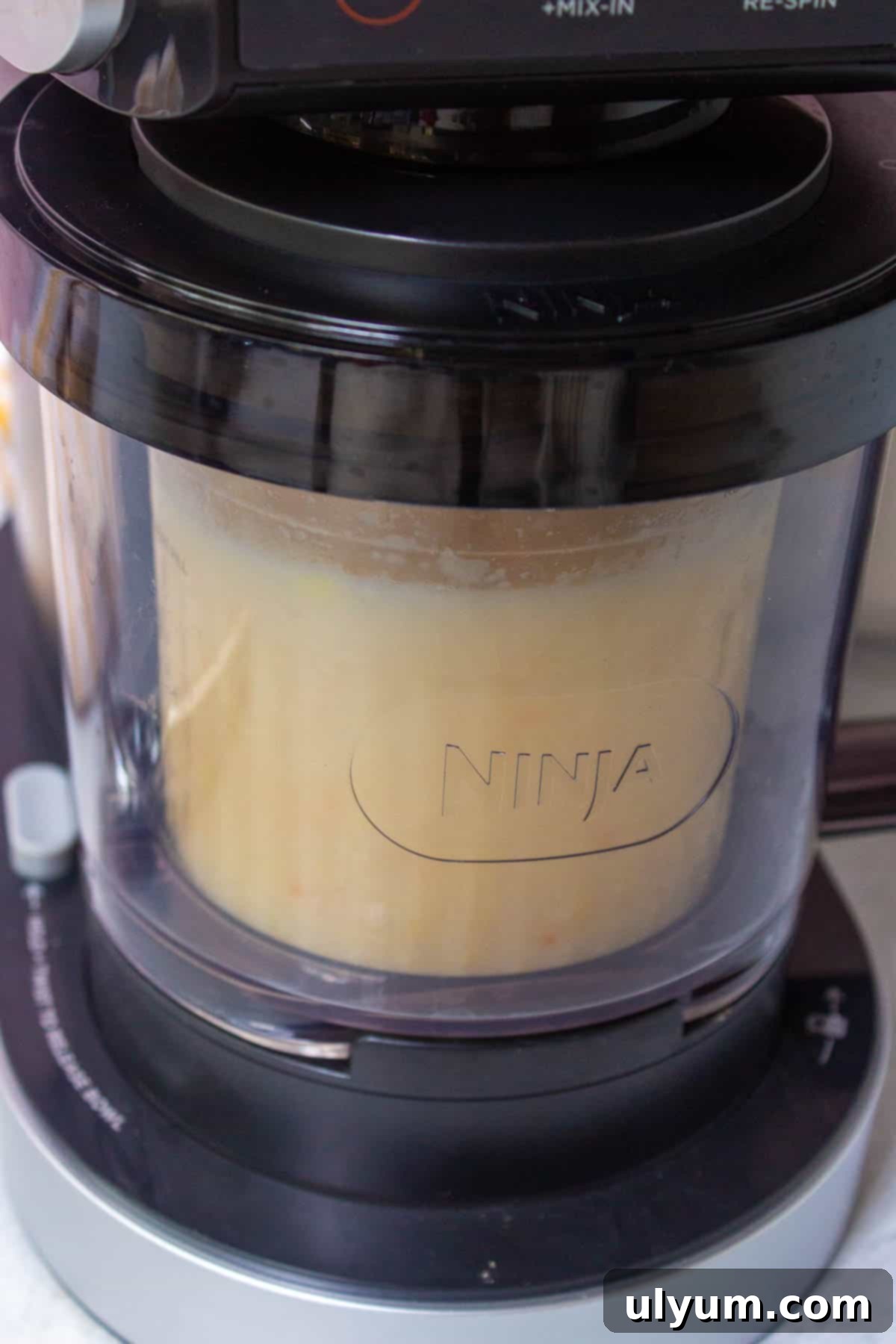 Ninja Creami machine assembly with pint inserted into the outer bowl and paddle attached to the lid