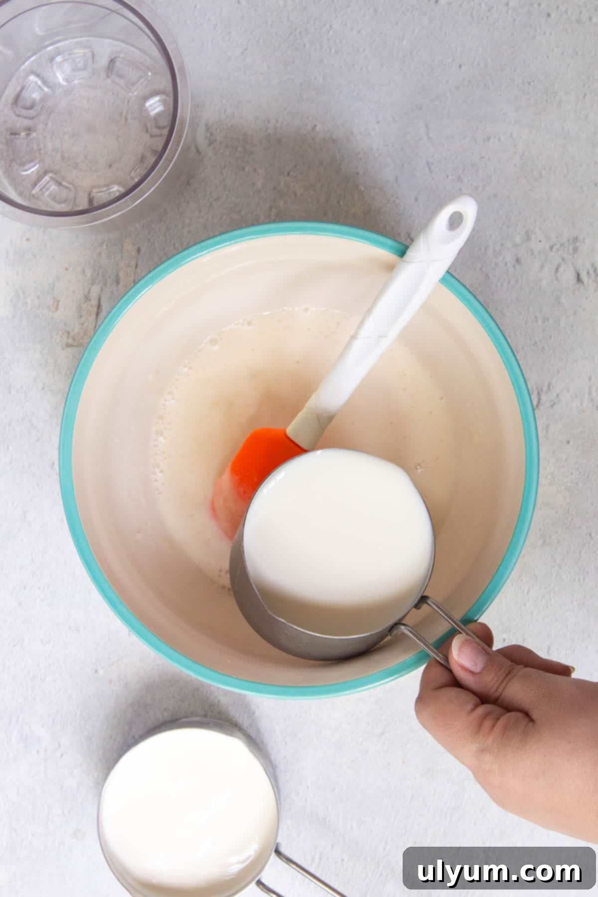 Whole milk and heavy cream are being mixed in little by little into the mixing bowl.