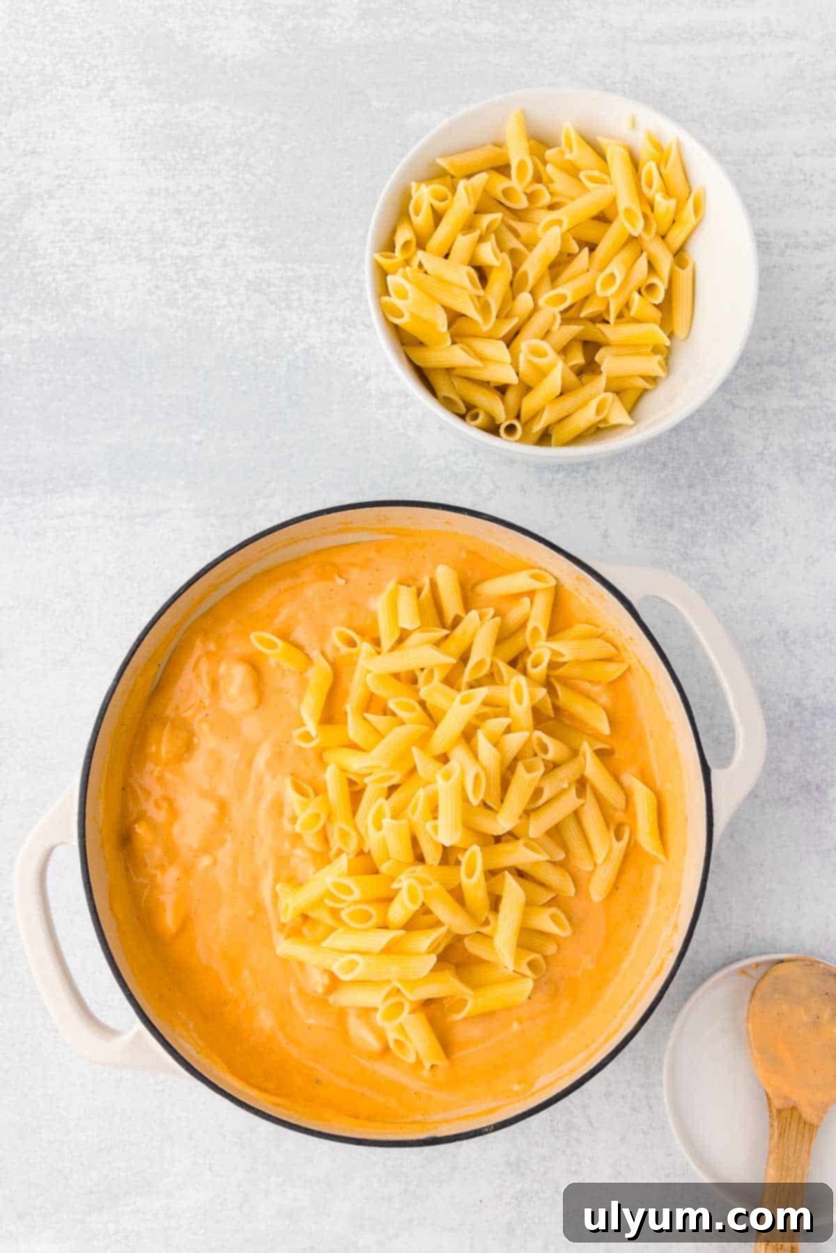 One-Pot Buffalo Chicken Mac and Cheese 10 Cooked penne is added to the large pot of buffalo cheese sauce, ready to be mixed