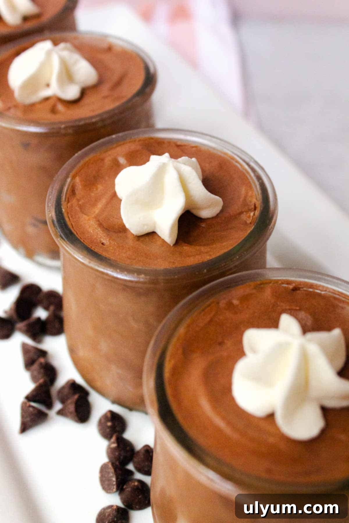 Elegant servings of 2-Ingredient Chocolate Mousse in clear glass jars, topped with whipped cream