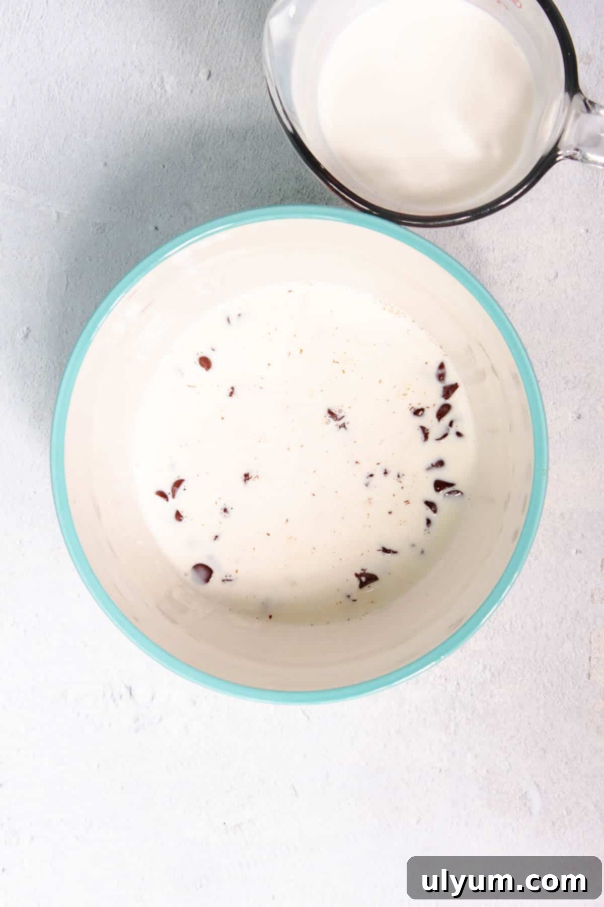 Chocolate chips fully submerged in warm heavy cream, ready to melt