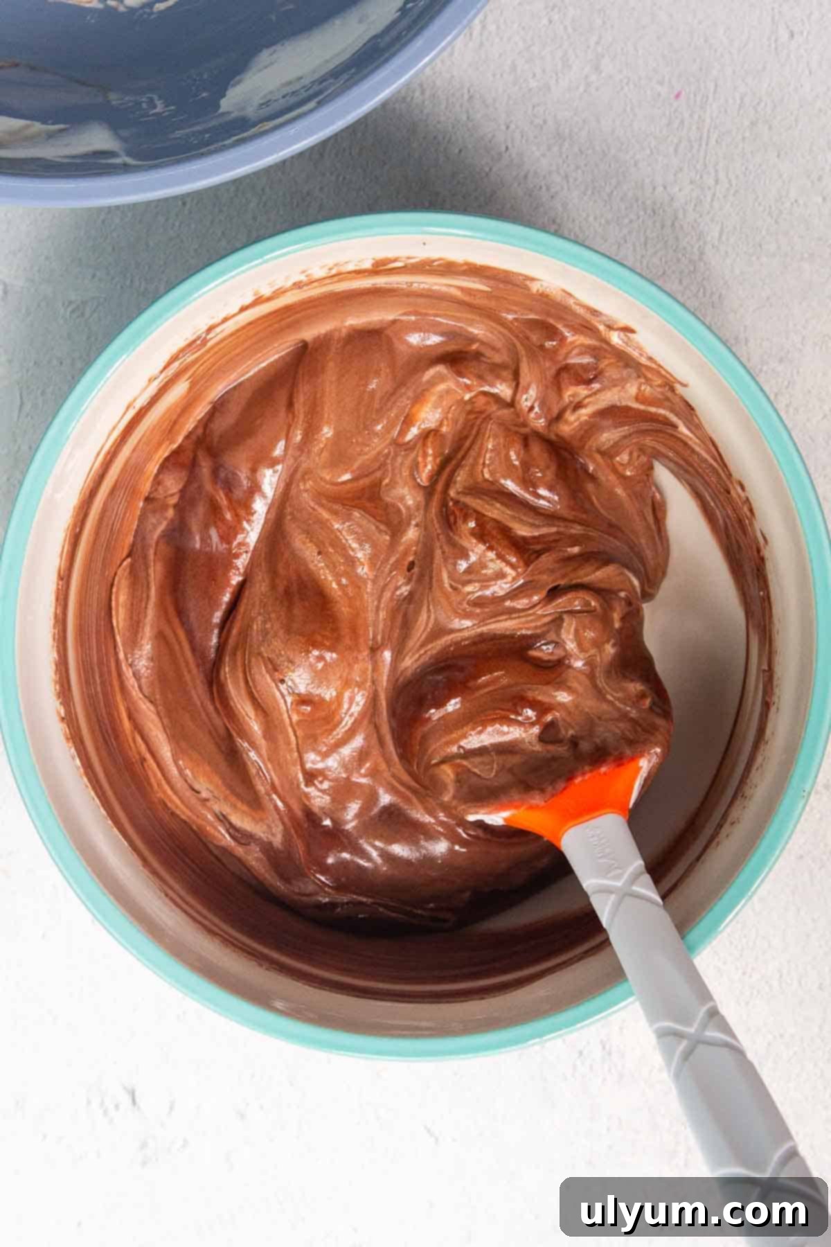 The chocolate mousse mixture is nearly fully combined, showing a few faint streaks of cream for optimal lightness