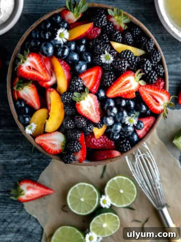 A vibrant Summer Fruit Salad with a mix of blueberries, strawberries, blackberries, and peaches, dressed in a refreshing lime, mint, honey, and ginger vinaigrette.