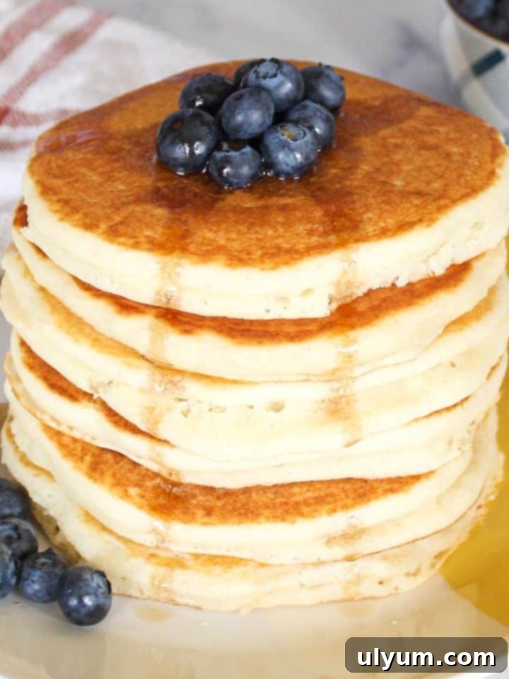 Fluffy Simple Bisquick Pancakes, topped with fresh blueberries and golden syrup.