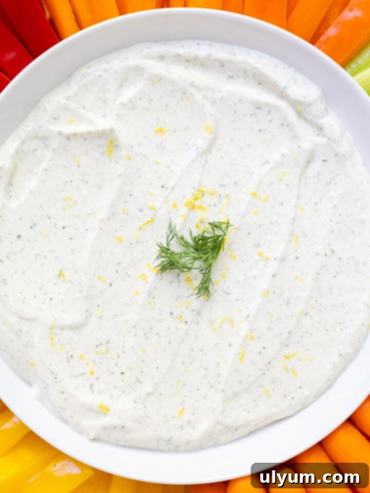 Creamy cottage cheese ranch dip on a serving platter with colorful fresh veggies including tri-color bell peppers, celery, and carrots.