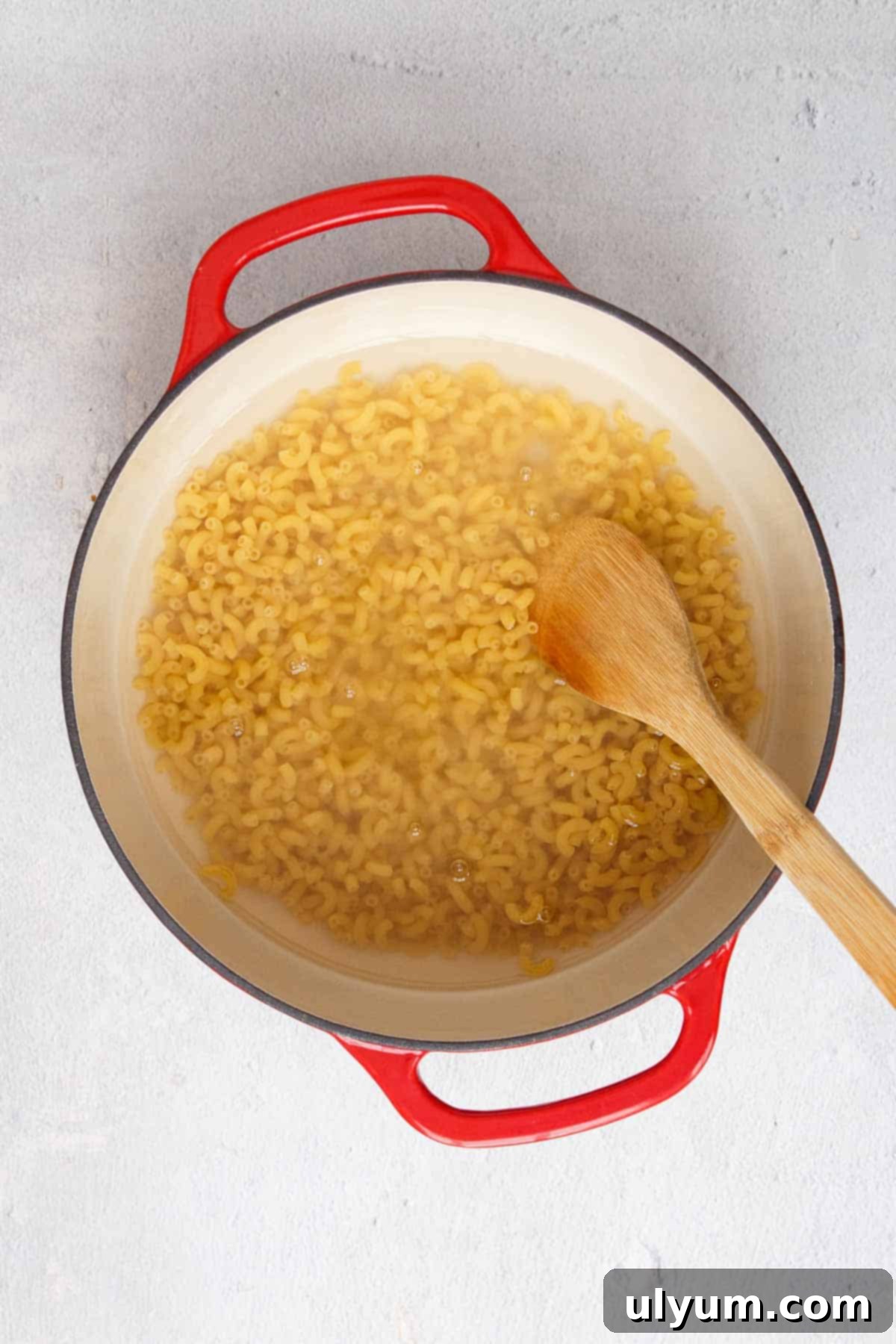 Boiling elbow macaroni in a large pot on the stovetop.