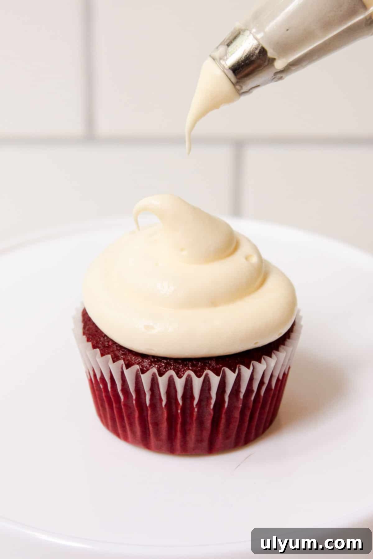 Cool Whip Cream Cheese Frosting 11 Cool Whip Cream Cheese Frosting being piped onto a red velvet cupcake with a 1A decorating tip, creating a perfect swirl.