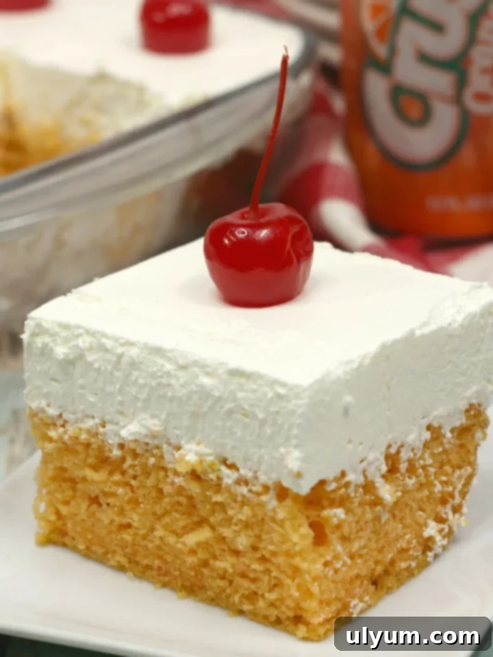 Slice of orange crush cake topped with a cherry