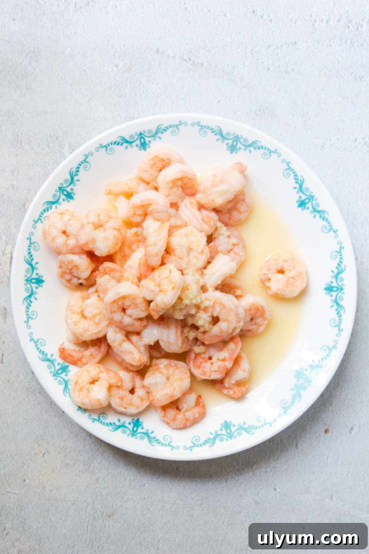 Cooked shrimp becomes pink in color and curls up. The cooked shrimp is set aside on a plate.