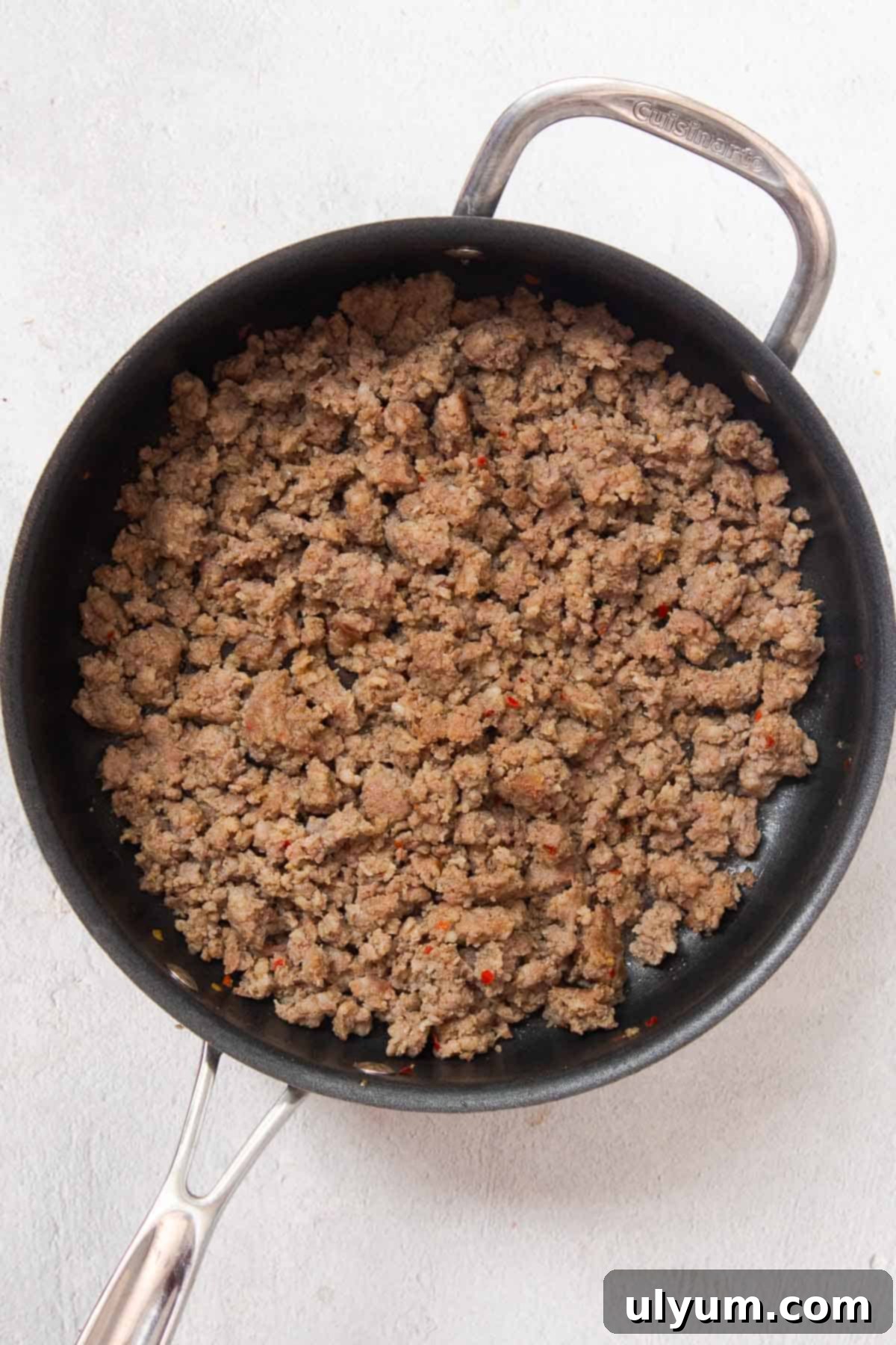 Ultimate Velveeta Sausage Dip 4 Close-up of browned and crumbled pork sausage in a large stainless steel skillet, ready for the next step of adding cheese and tomatoes.