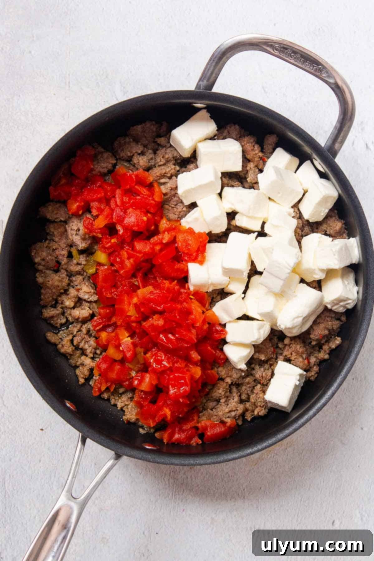 Rotel diced tomatoes and diced cream cheese added to the browned pork sausage in a large skillet