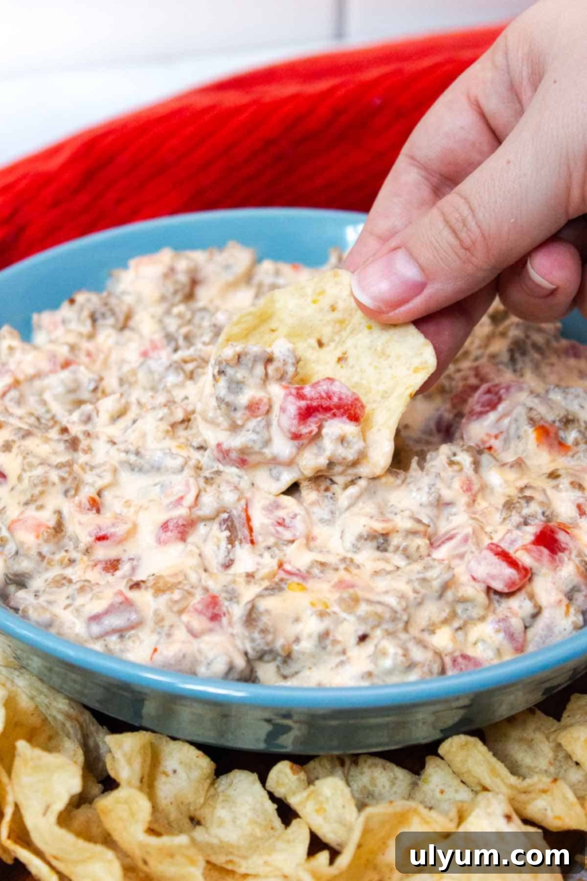 Tortilla chip scooping up cream cheese sausage dip to show chunky consistency