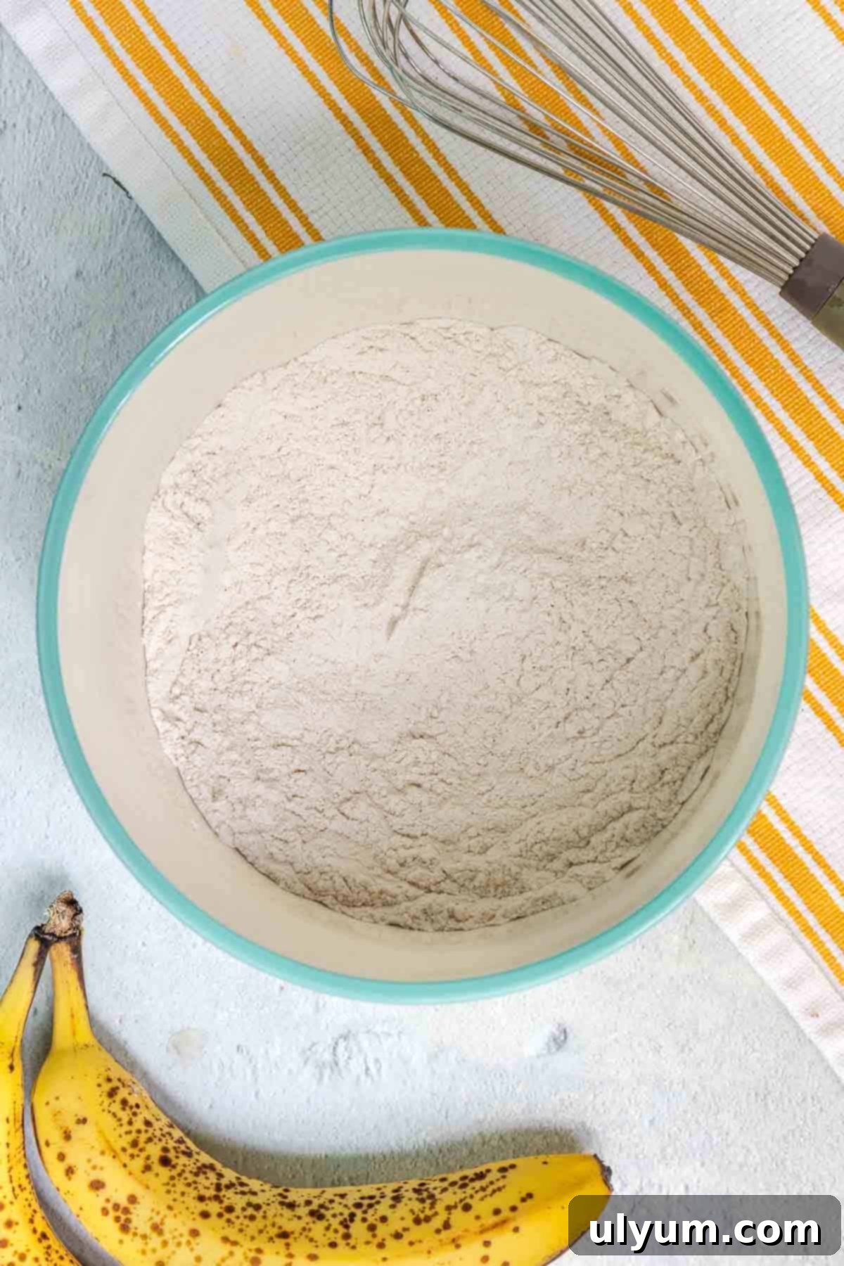 Dry ingredients for the banana coffee cake - flour, baking powder, baking soda, cinnamon, and salt - mixed in a medium bowl.