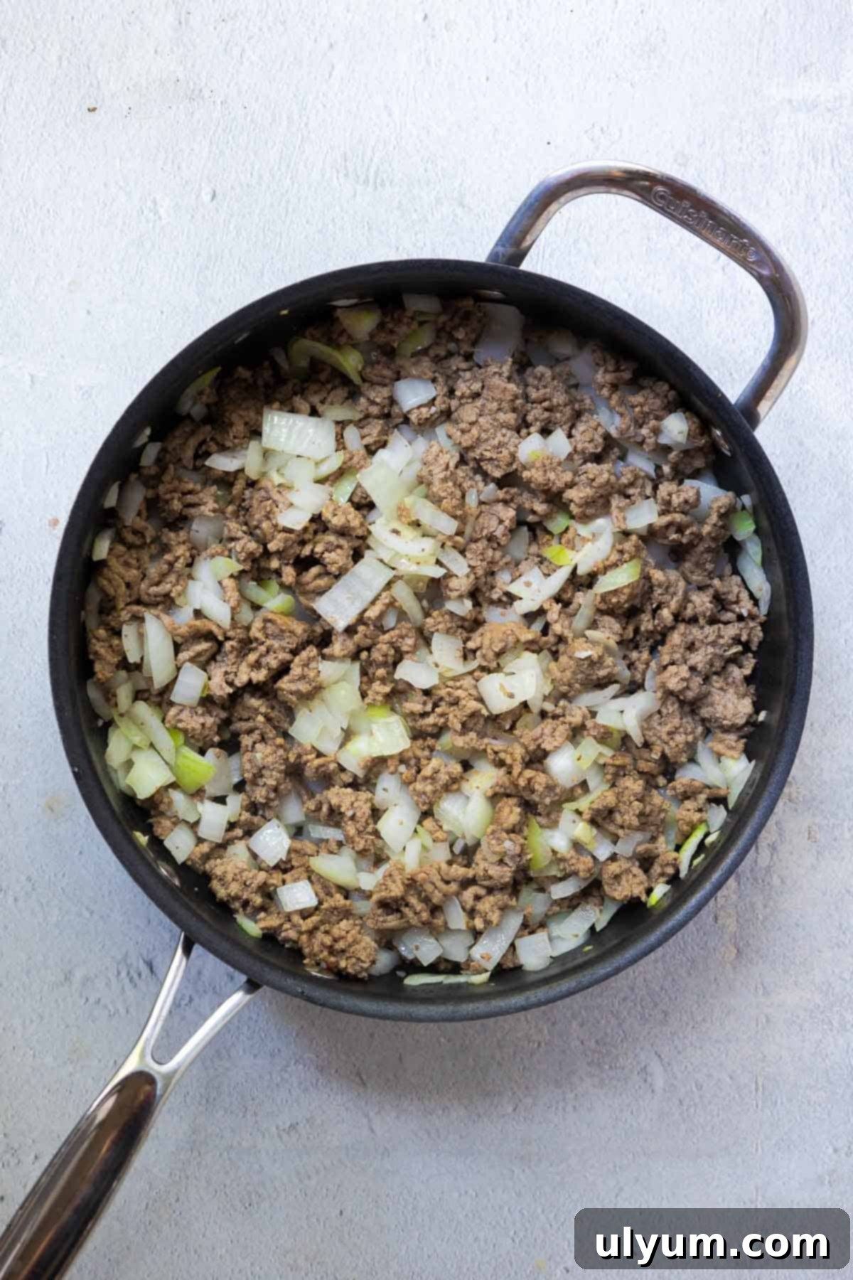 Diced onions are added to the browned meat and cooked until translucent, infusing the mixture with flavor.