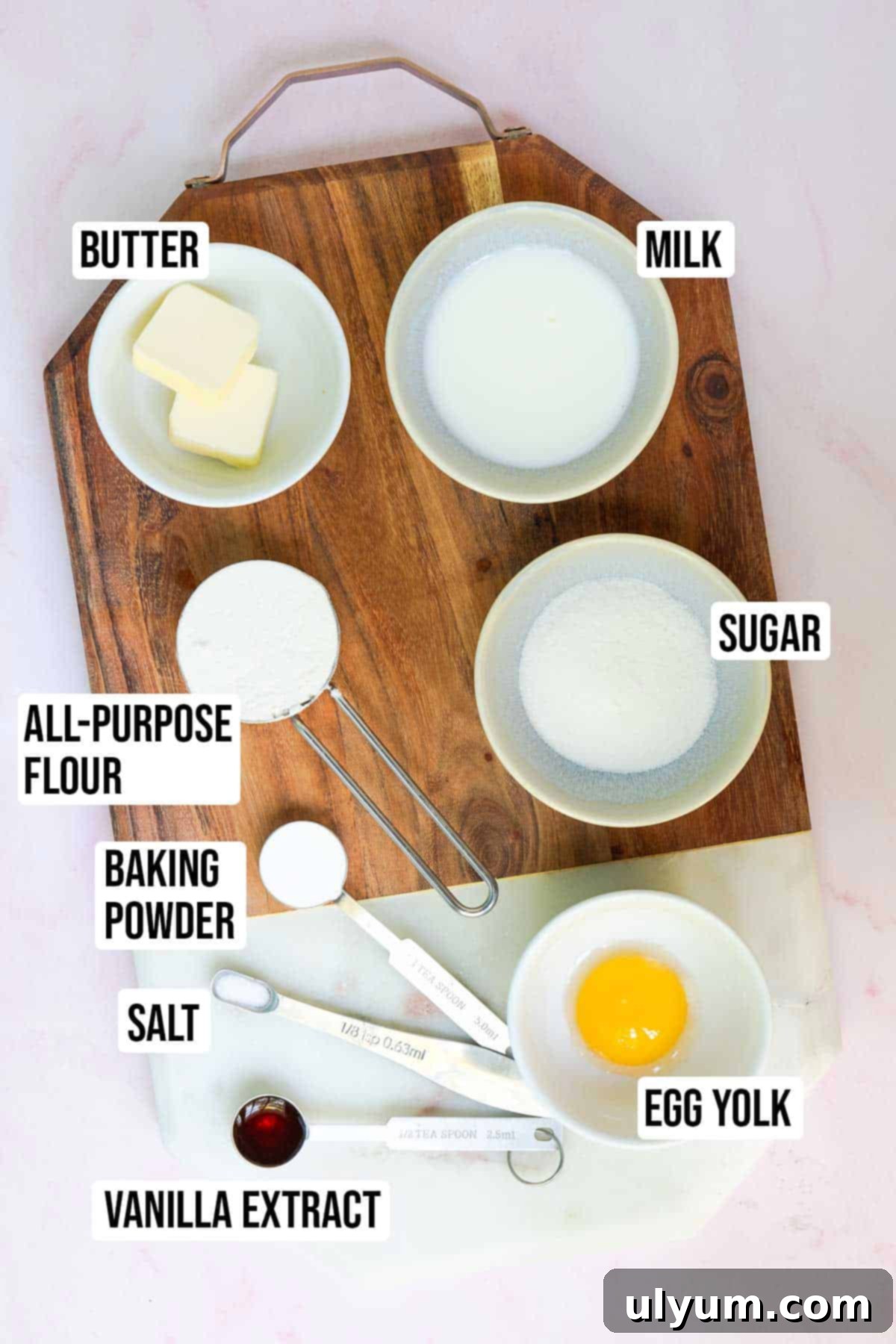 Yellow mug cake ingredients: butter, milk, vanilla extract, egg yolk, all-purpose flour, granulated sugar, baking powder, and table salt.