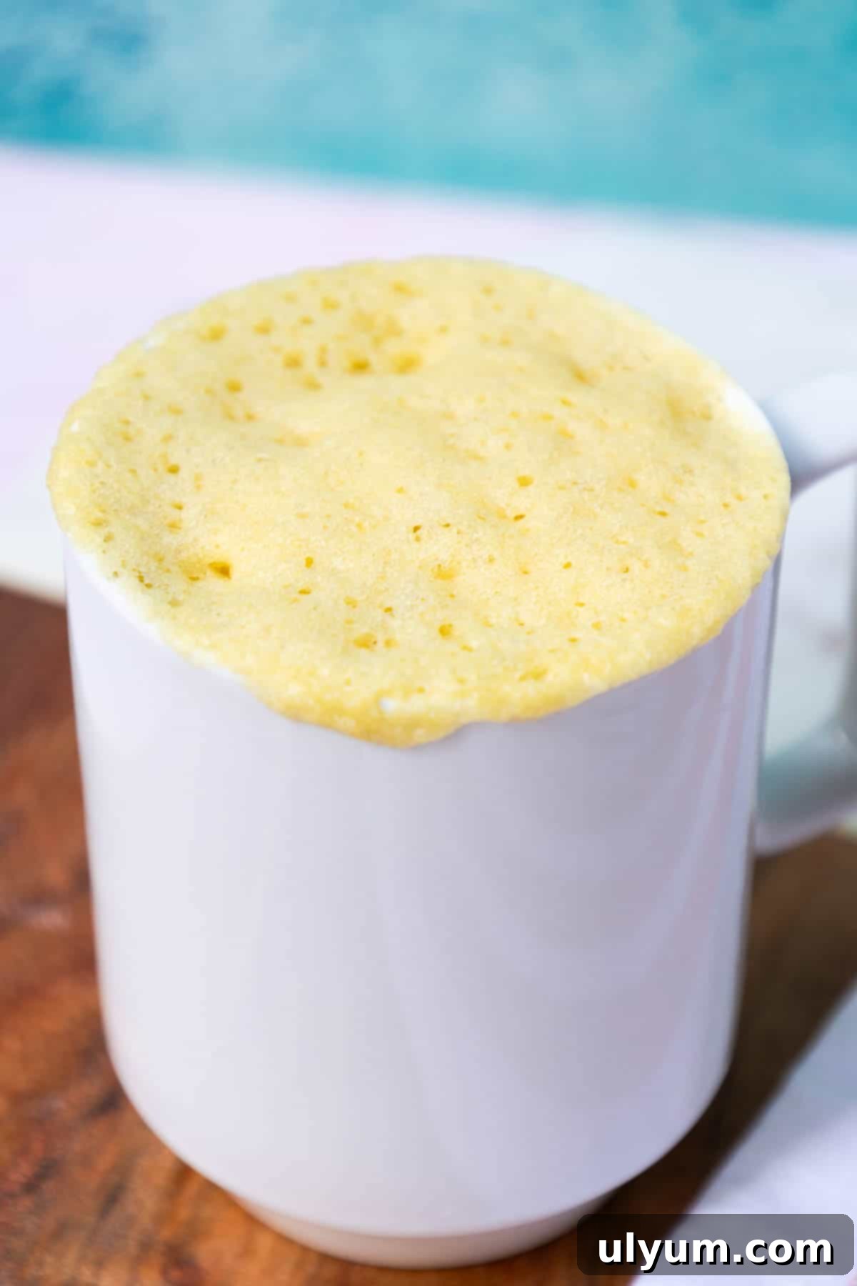 The cake is cooked. The cake has risen to be level with the top of the mug.