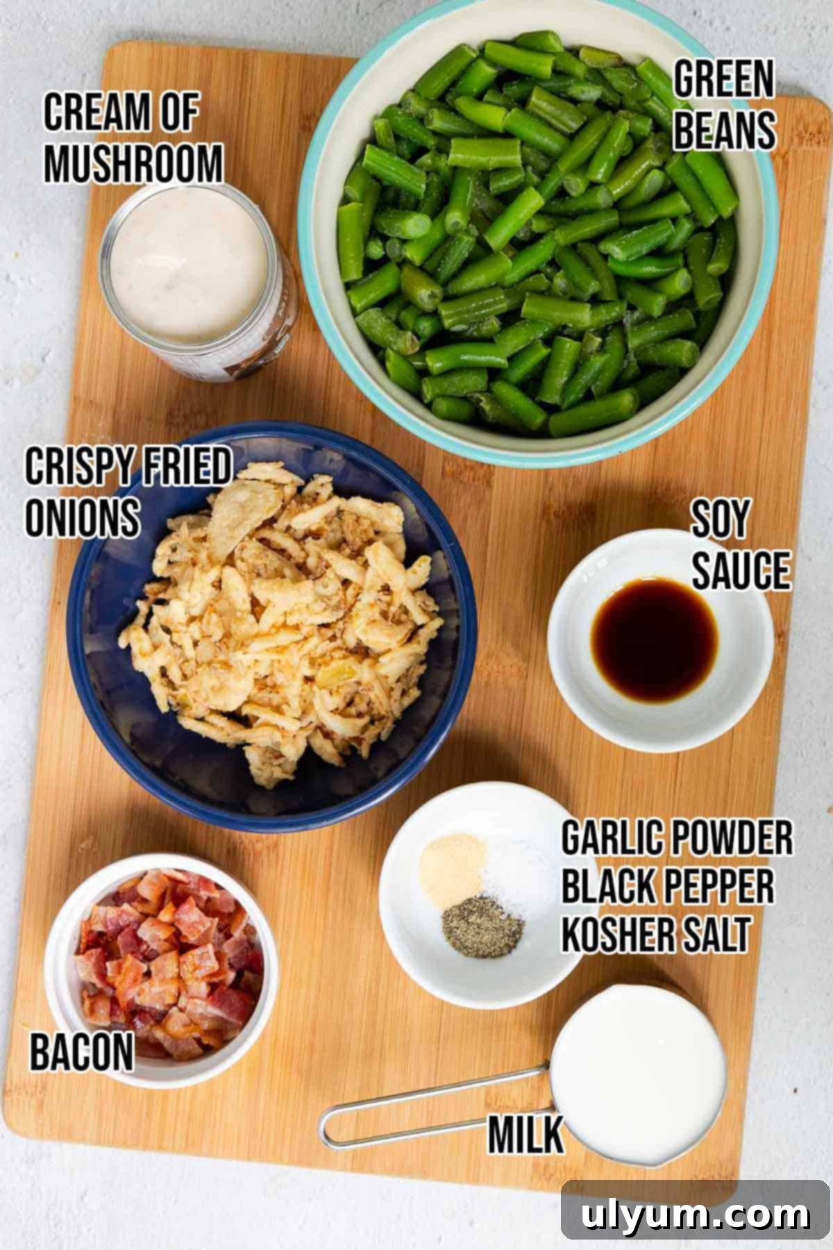 Green bean casserole with bacon ingredients: frozen green beans, bacon, crispy fried onions, cream of mushroom soup, milk, soy sauce, garlic powder, black pepper, and kosher salt.