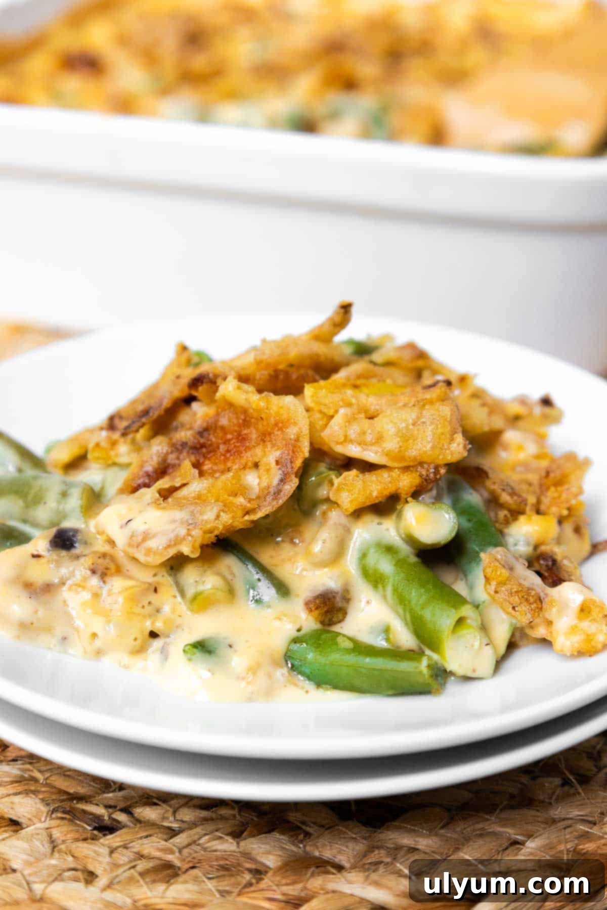A small plate of Velveeta green bean casserole garnished with fresh herbs, showcasing its creamy texture.