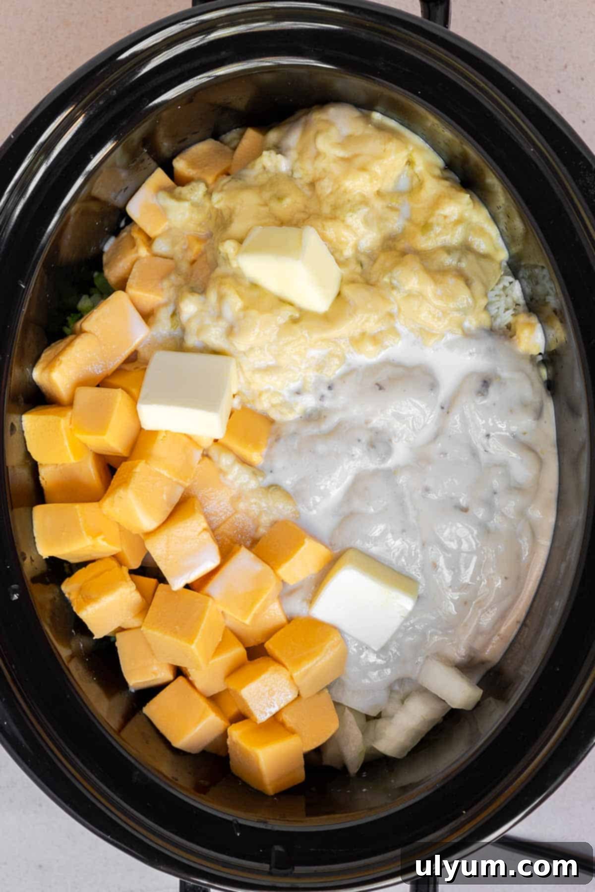 All of the ingredients except the shredded cheddar are added to the crock of a slow cooker.