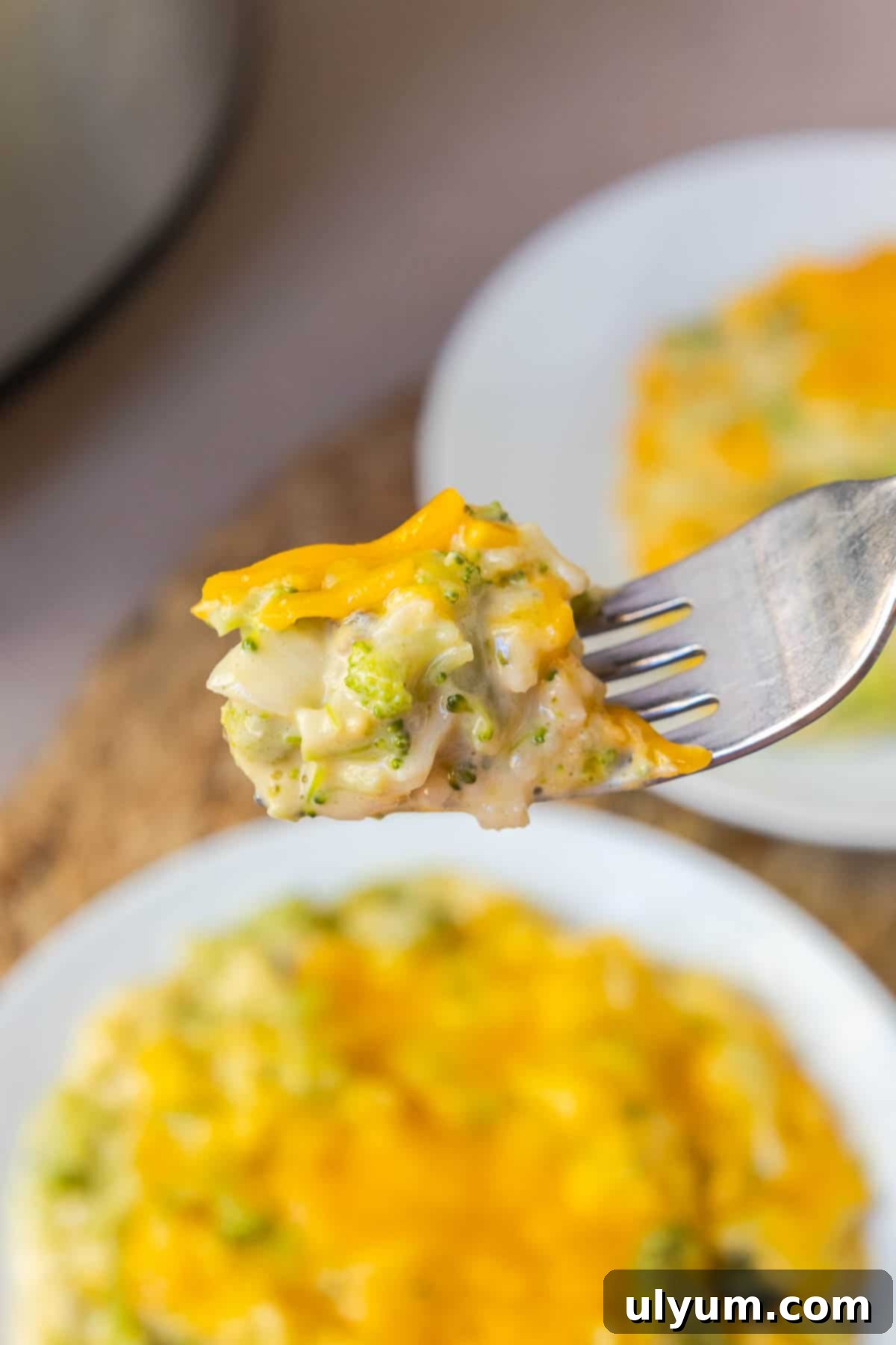 A fork lifting a bite of creamy Crockpot Broccoli Rice Casserole, showing the melted cheese and tender ingredients.
