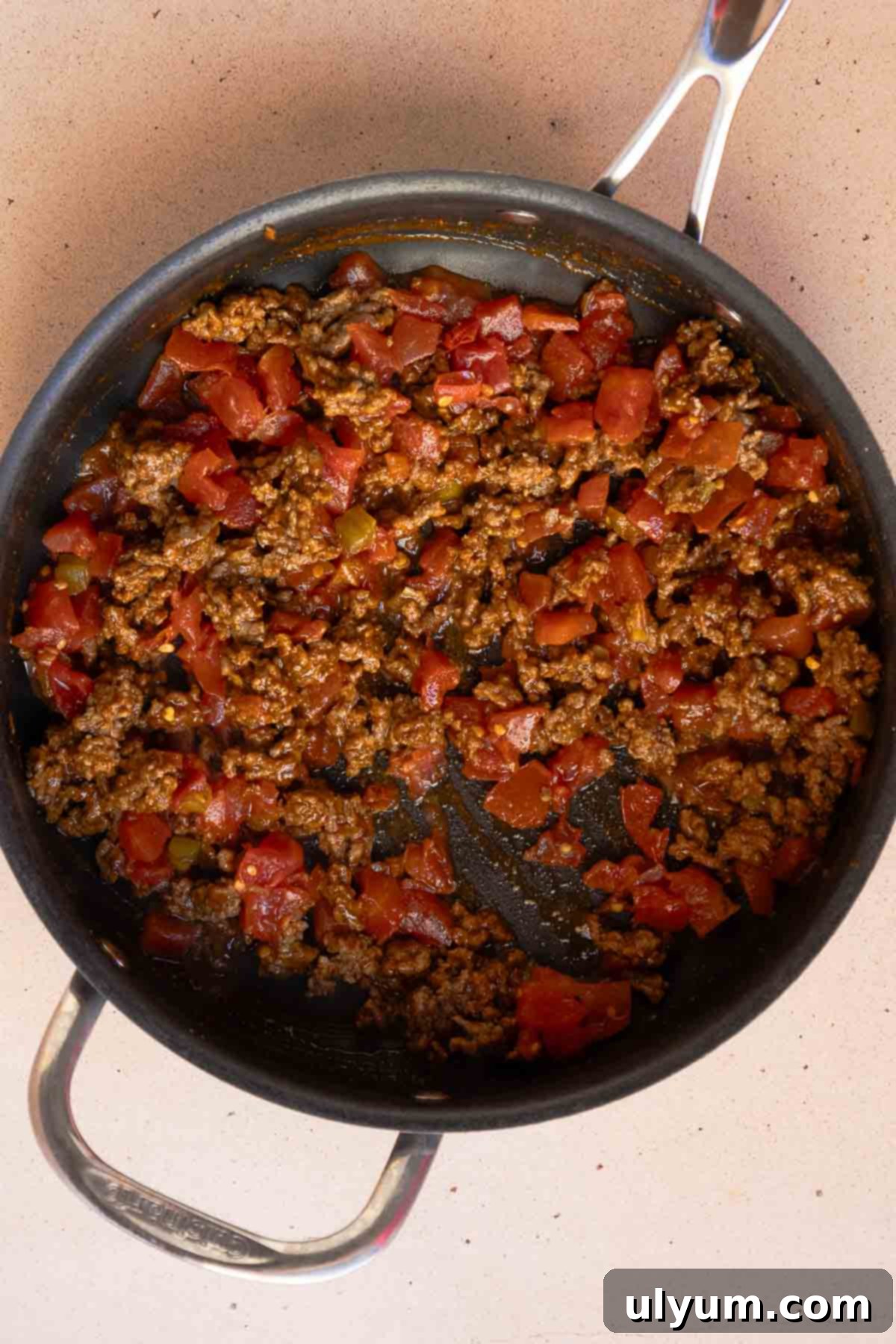The ground beef and drained Rotel are combined in a large saucepan, creating the savory top layer for the casserole.