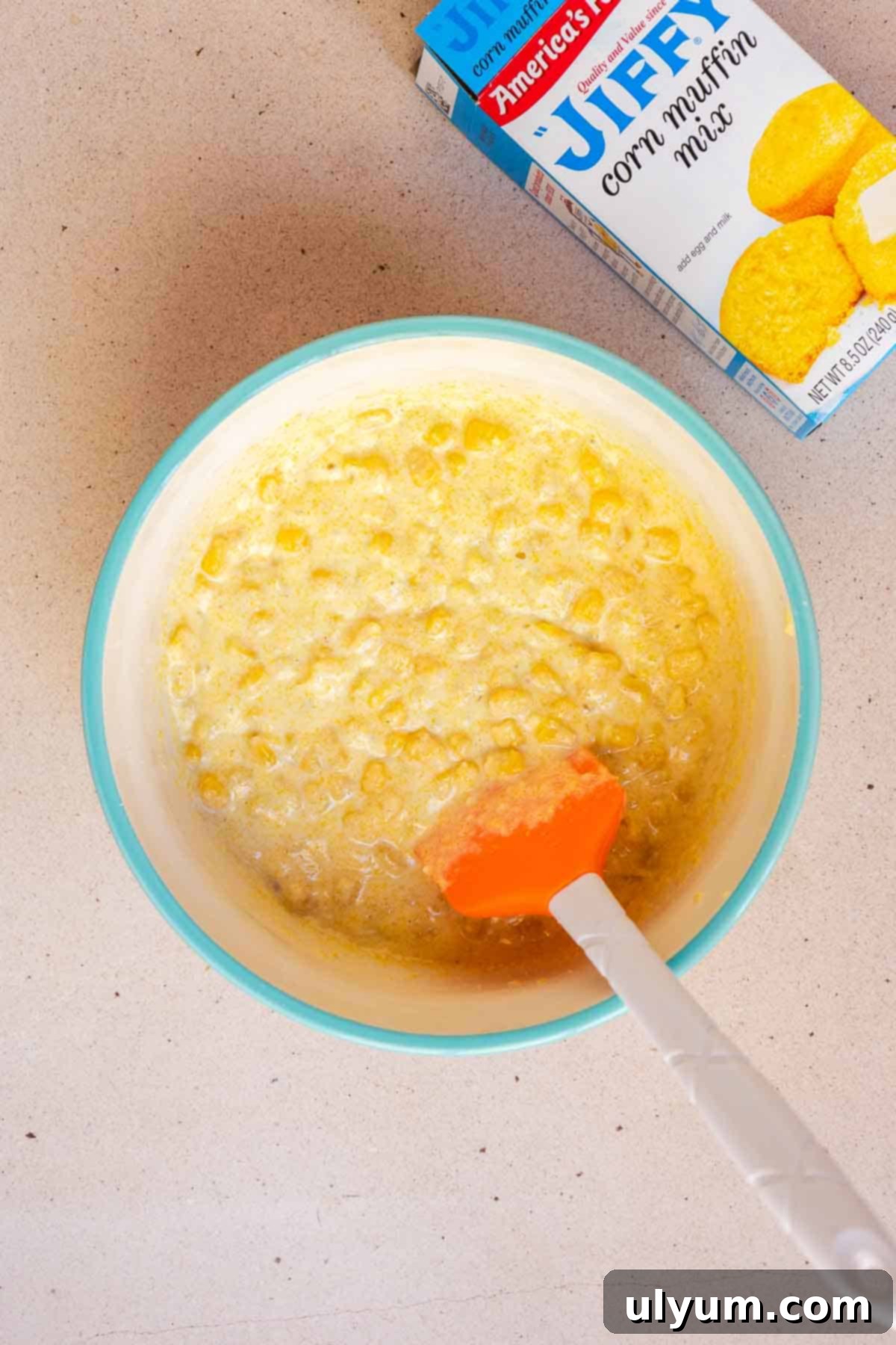The Jiffy corn muffin mix, milk, and egg are being combined in a medium mixing bowl, forming the base for the cornbread layer.