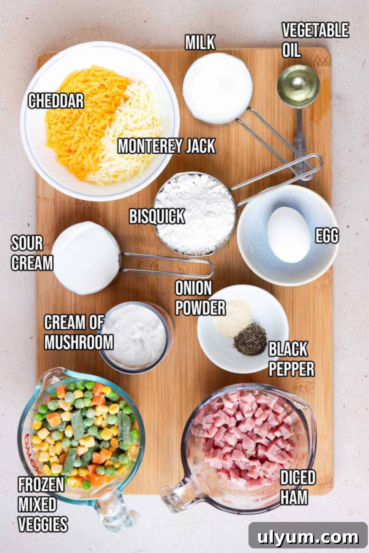 All the fresh ingredients for a ham and vegetable casserole laid out on a wooden surface.