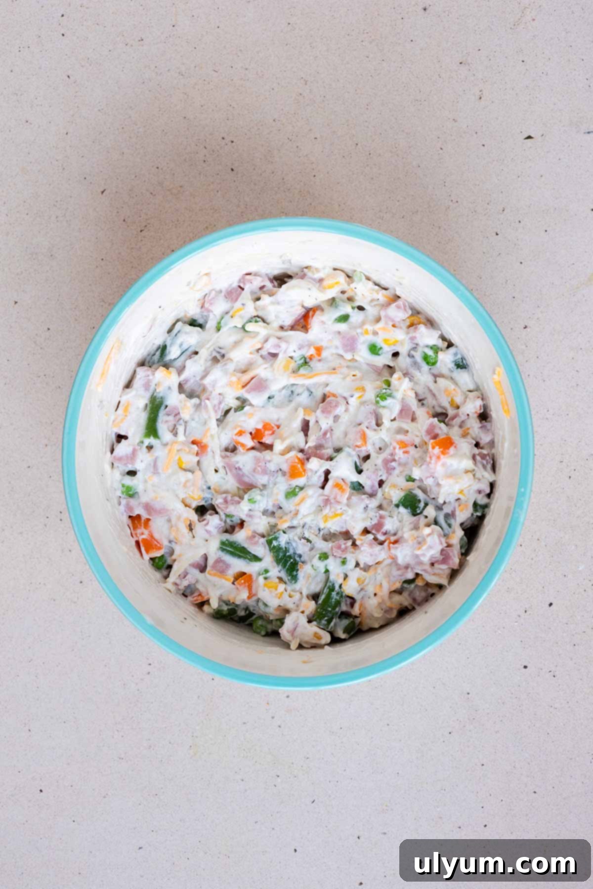 The ham and vegetable mixture is combined in a medium mixing bowl, showing the creamy base and colorful ingredients.
