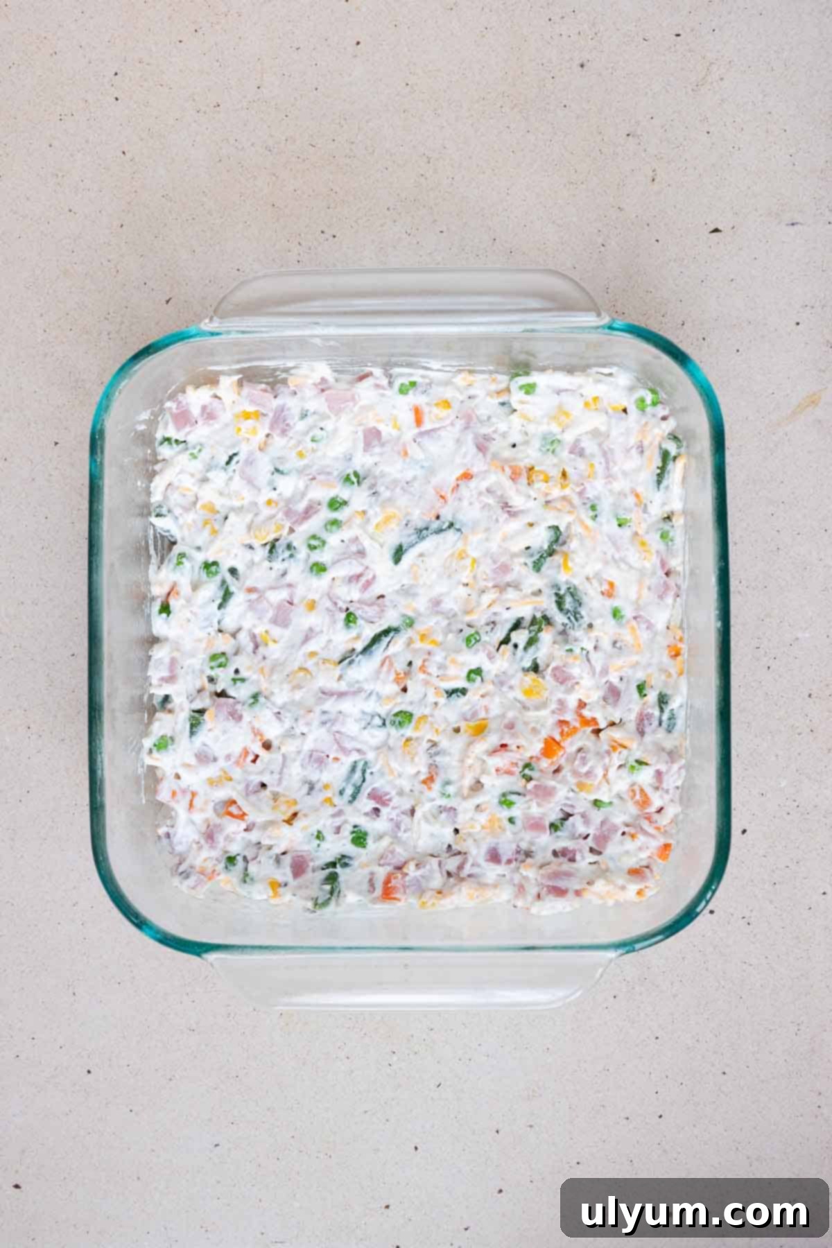The ham filling is spread evenly into an 8 by 8 inch casserole dish, ready for the topping.