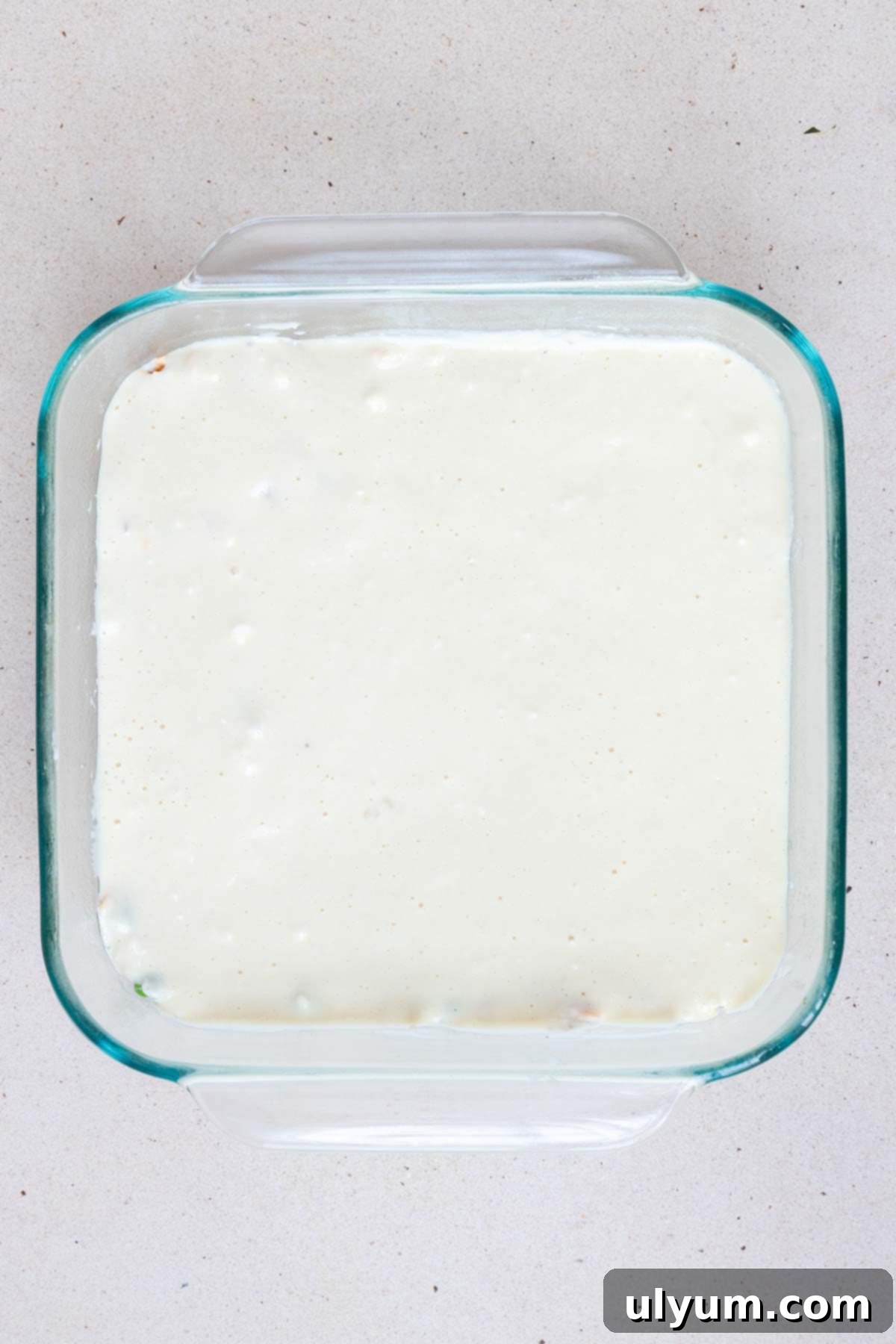 The Bisquick mixture is poured and spread into an even layer over the ham mixture, covering the entire surface.