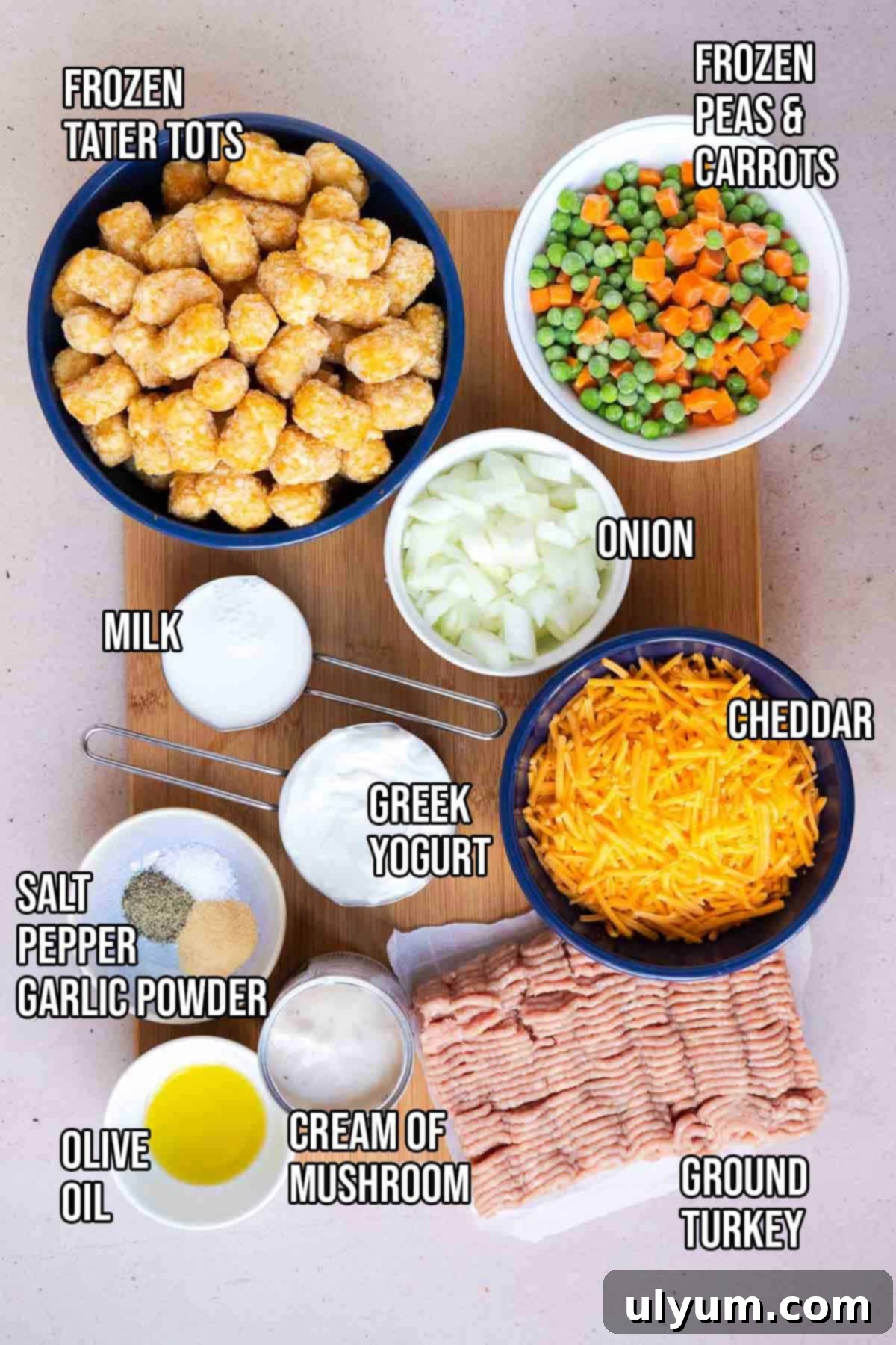 Turkey tater tot casserole ingredients: olive oil, ground turkey, yellow onion, cream of mushroom soup, Greek yogurt, shredded cheddar, milk, frozen peas and carrots, salt, pepper, garlic powder, and frozen tater tots.