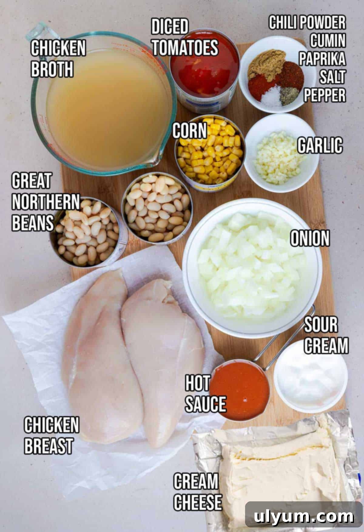 Slow cooker buffalo chicken chili ingredients: chicken breasts, Great Northern Beans, corn, onion, garlic, diced tomatoes, chicken broth, chili seasoning, sour cream, and cream cheese.