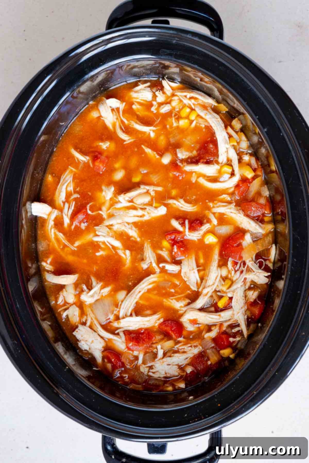 The shredded chicken is returned to the slow cooker.
