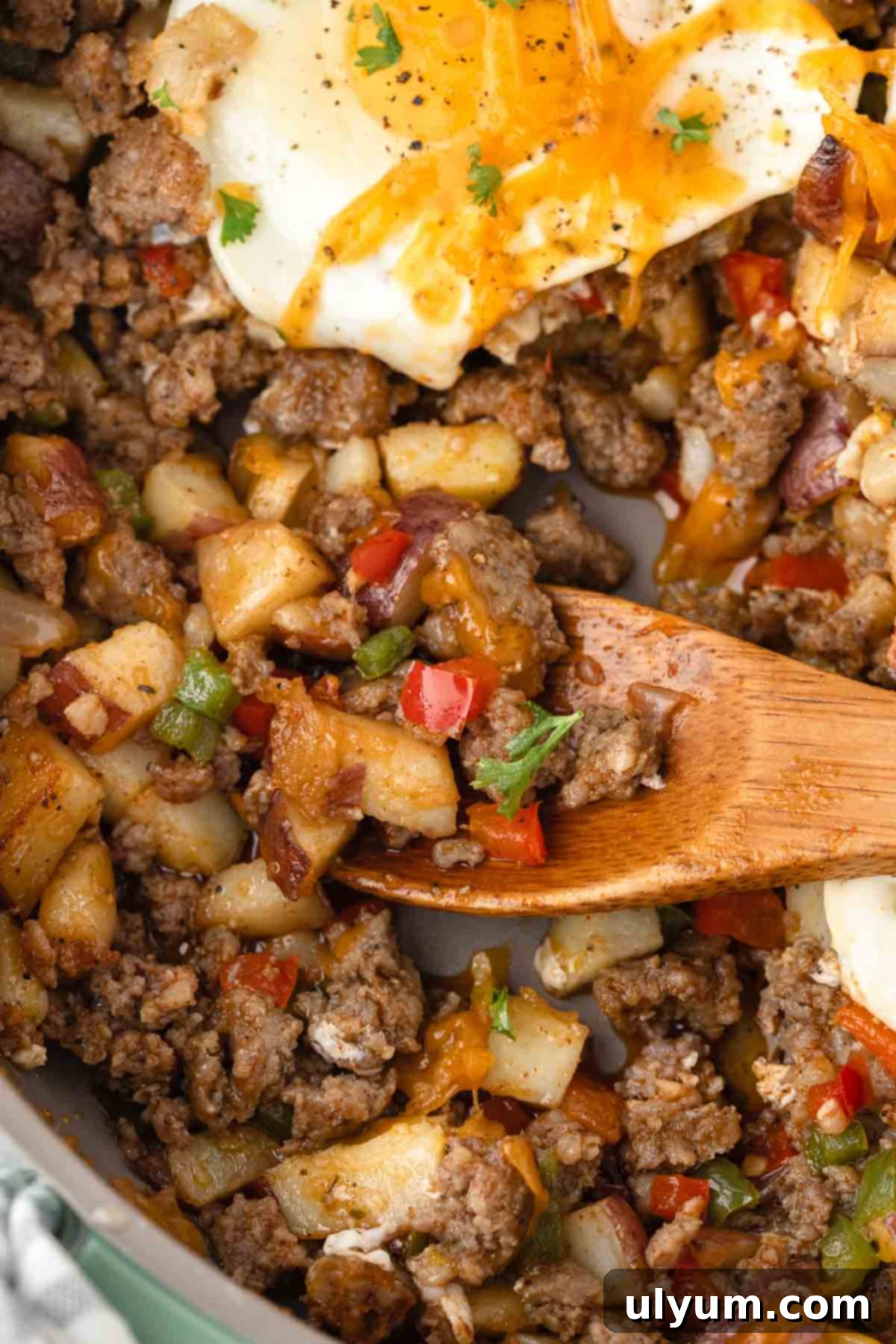 Breakfast sausage potato hash with potatoes, sausage, bell peppers, onion, cheese, and eggs.